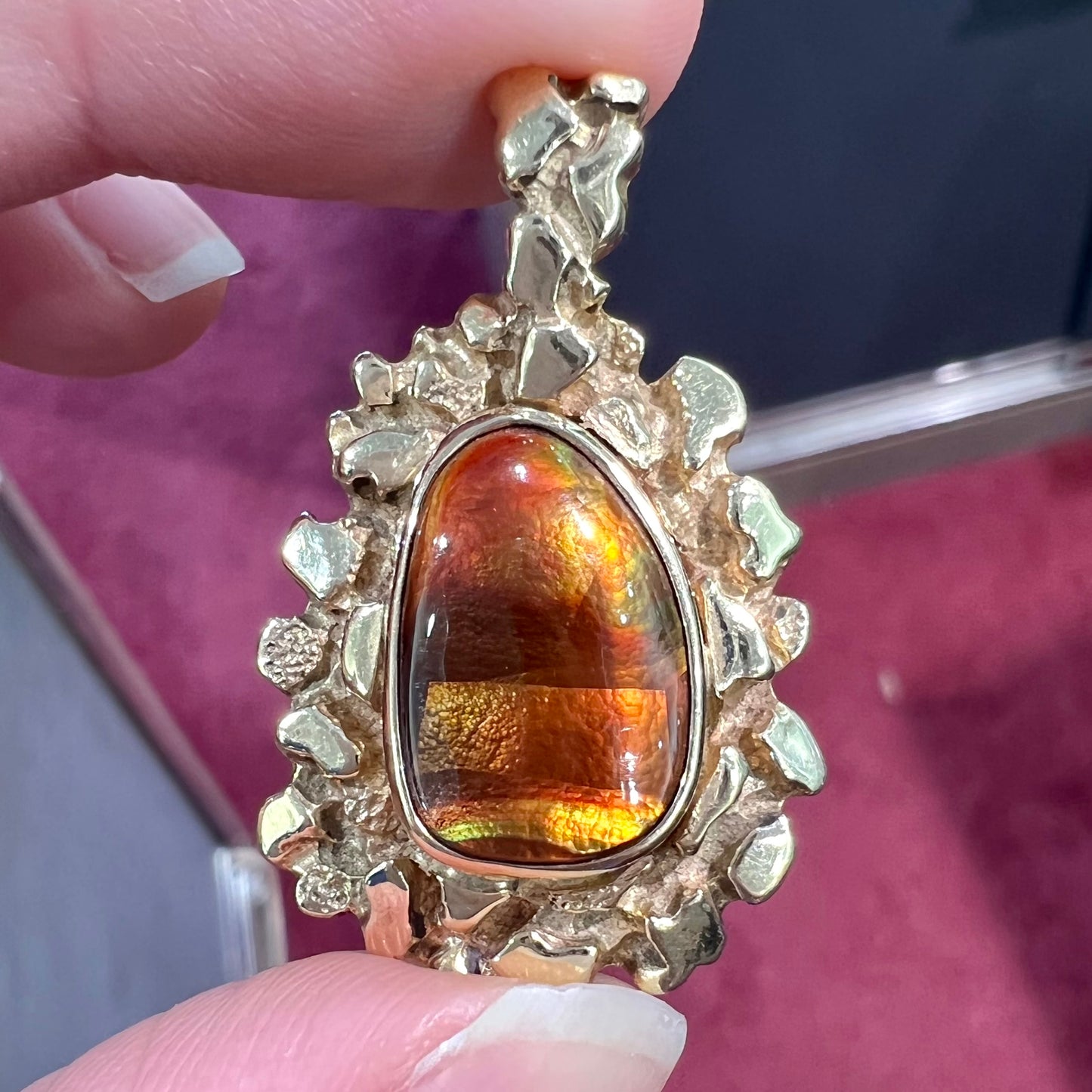 A gold nugget style pendant set with a freeform cabochon cut fire agate stone.