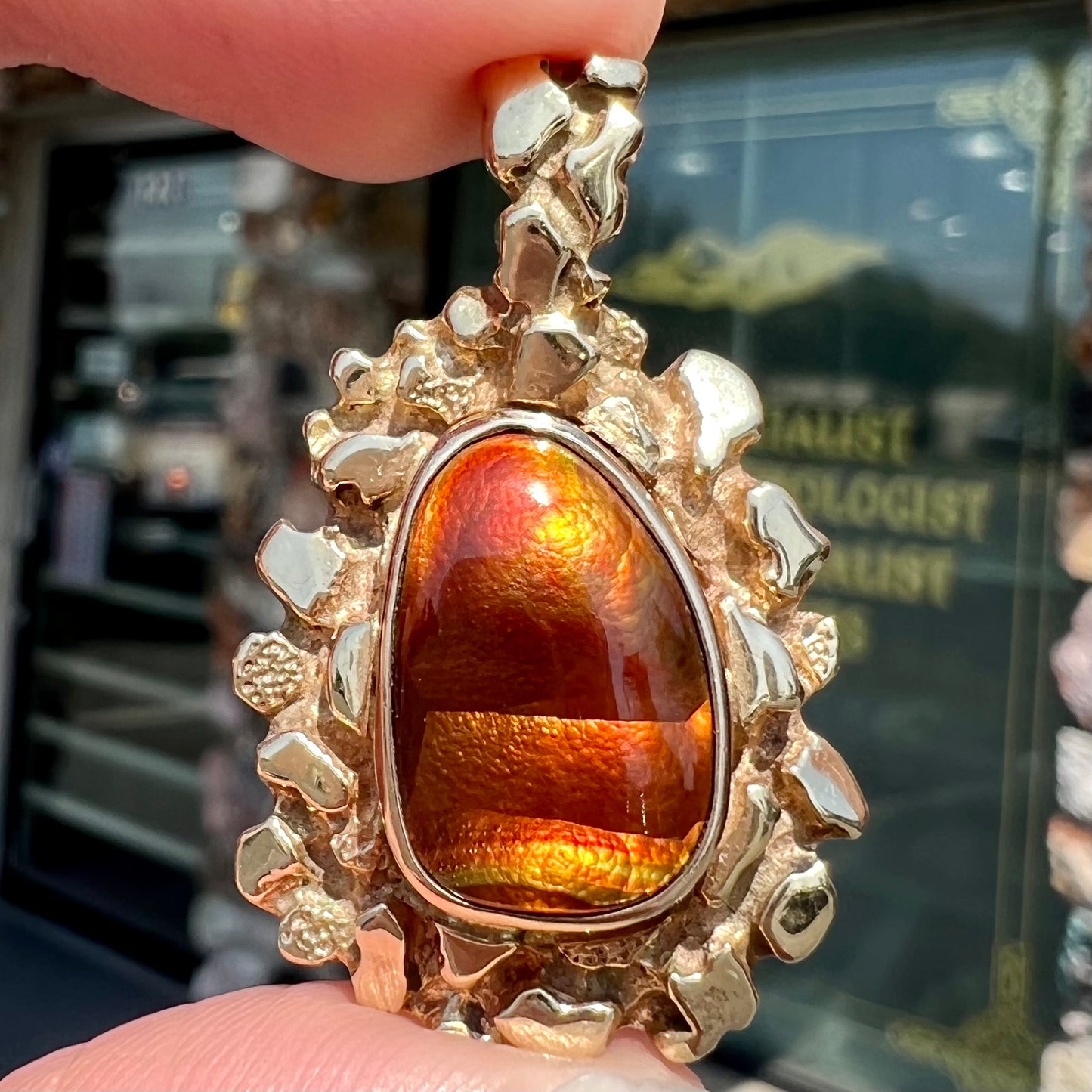 A gold nugget style pendant set with a freeform cabochon cut fire agate stone.