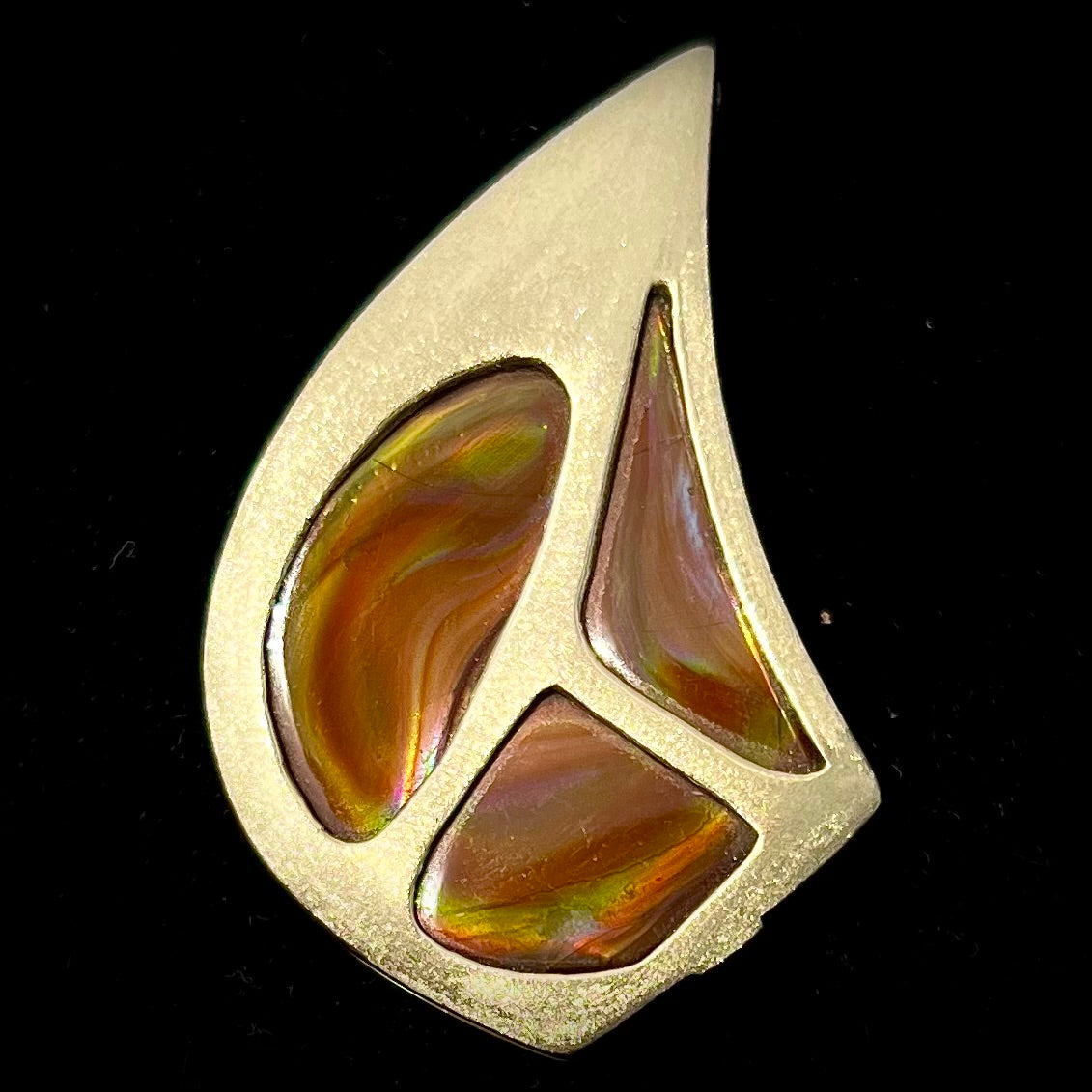 A men's gold pendant set with three fire agate stones.  The fire agate resembles an oil slick puddle.