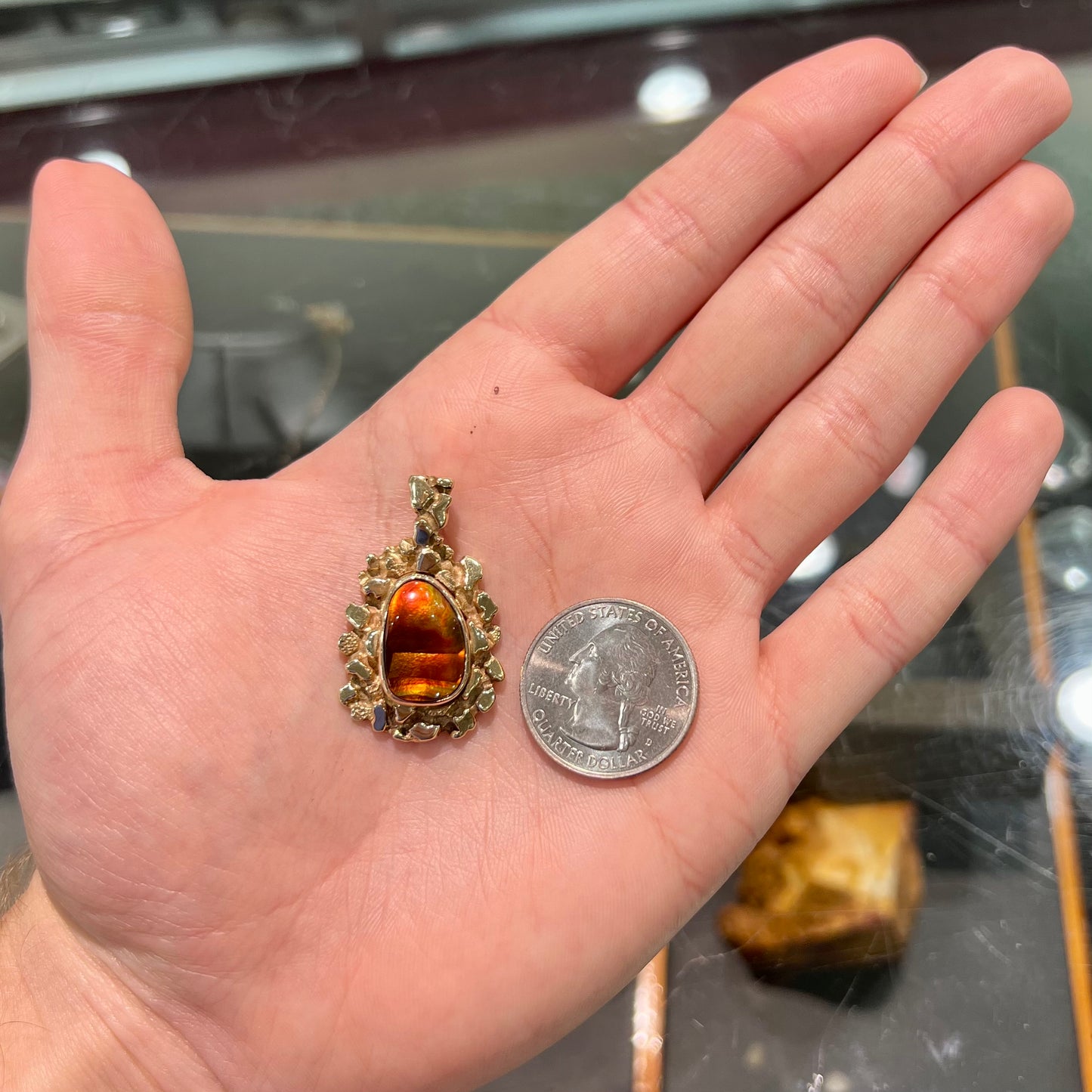 A gold nugget style pendant set with a freeform cabochon cut fire agate stone.