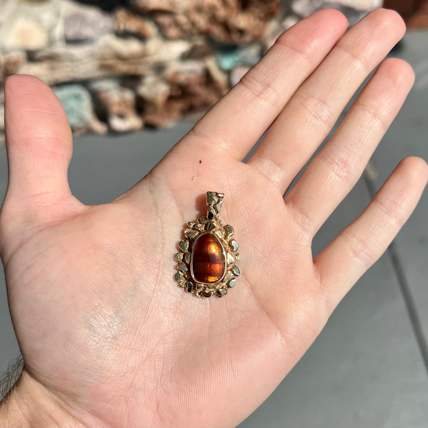 A gold nugget style pendant set with a freeform cabochon cut fire agate stone.