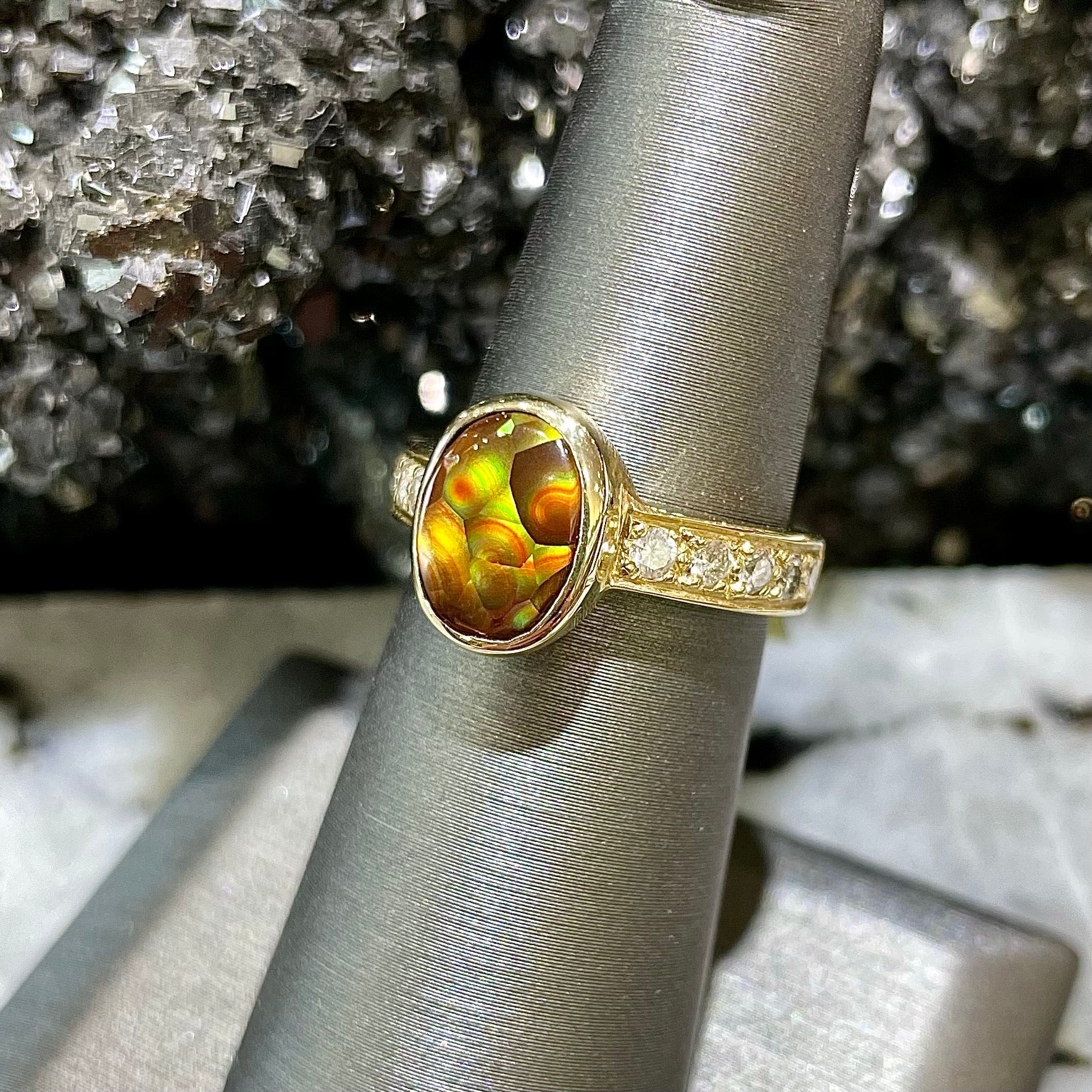 A ladies' oval cabochon cut fire agate and diamond engagement ring cast in yellow gold.