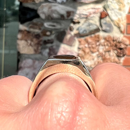 A men's yellow gold flush set fire agate solitaire ring.  The fire agate displays flashes of green, orange, and yellow.