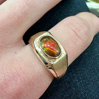 A yellow gold men's fire agate solitaire ring.  The fire agate is red with green undertones.