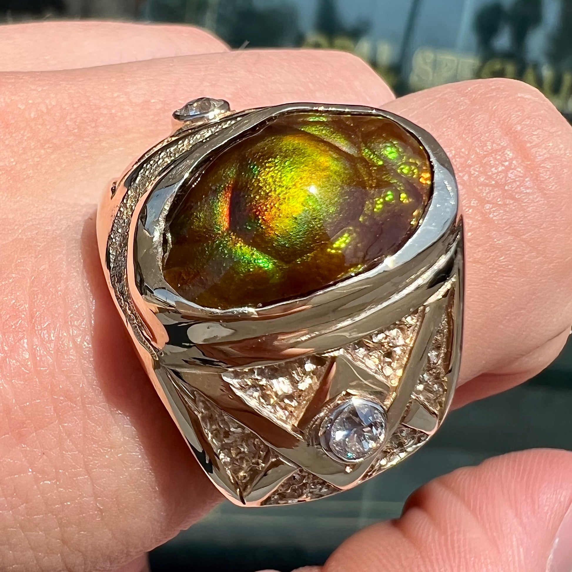 A men's solid yellow gold fire agate and diamond ring.  The fire agate displays predominantly red and green.