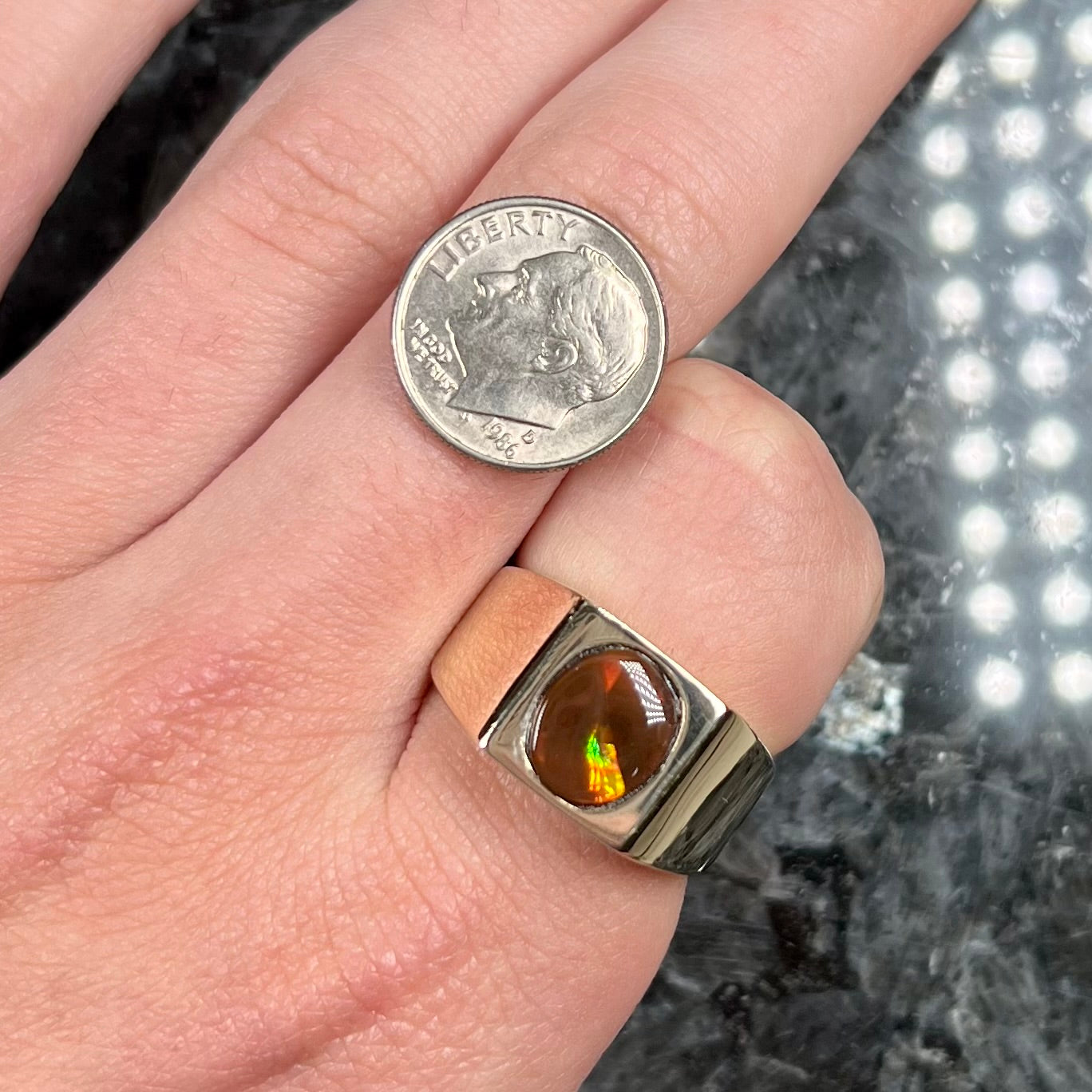 A men's yellow gold flush set fire agate solitaire ring.  The fire agate displays flashes of green, orange, and yellow.