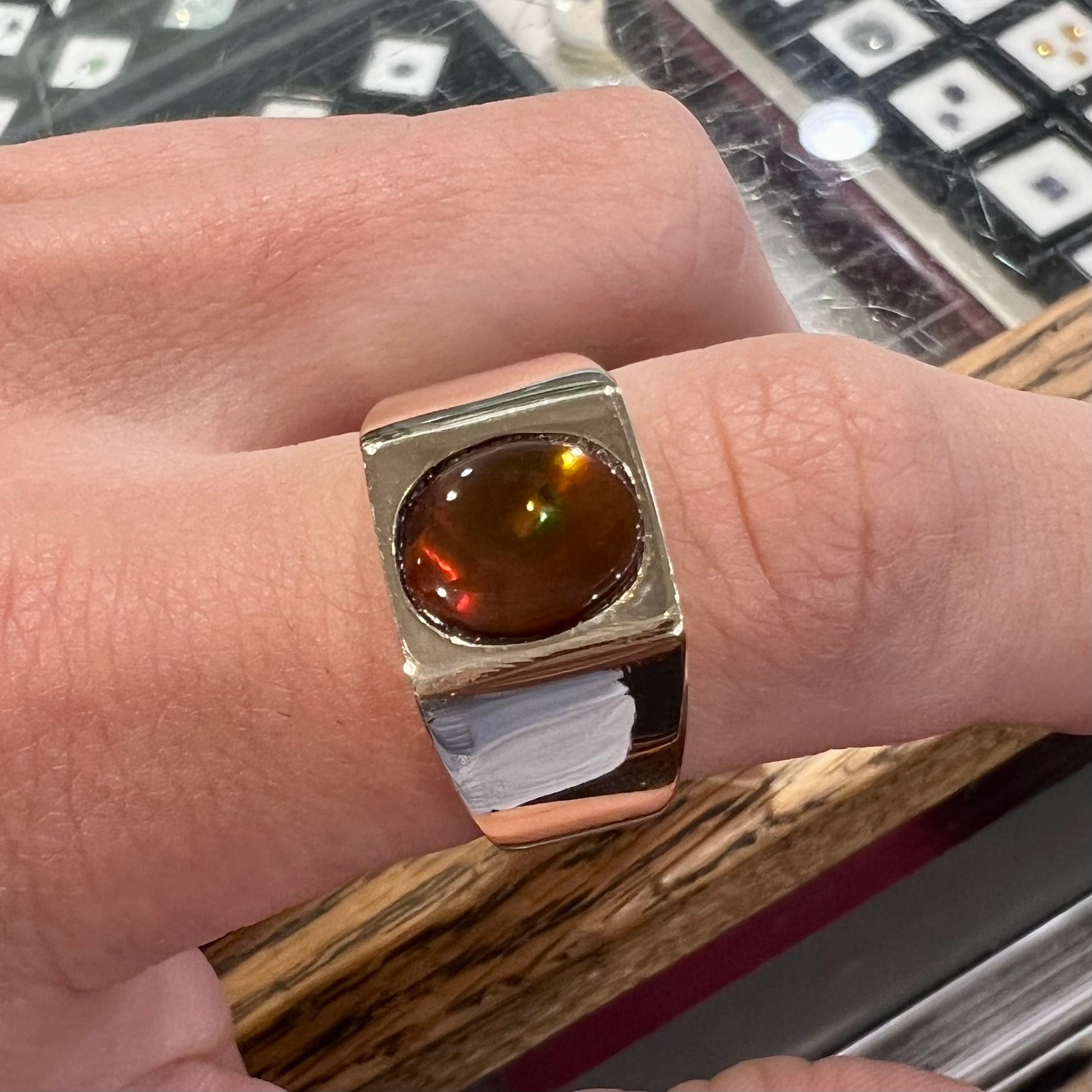 A men's yellow gold flush set fire agate solitaire ring.  The fire agate displays flashes of green, orange, and yellow.
