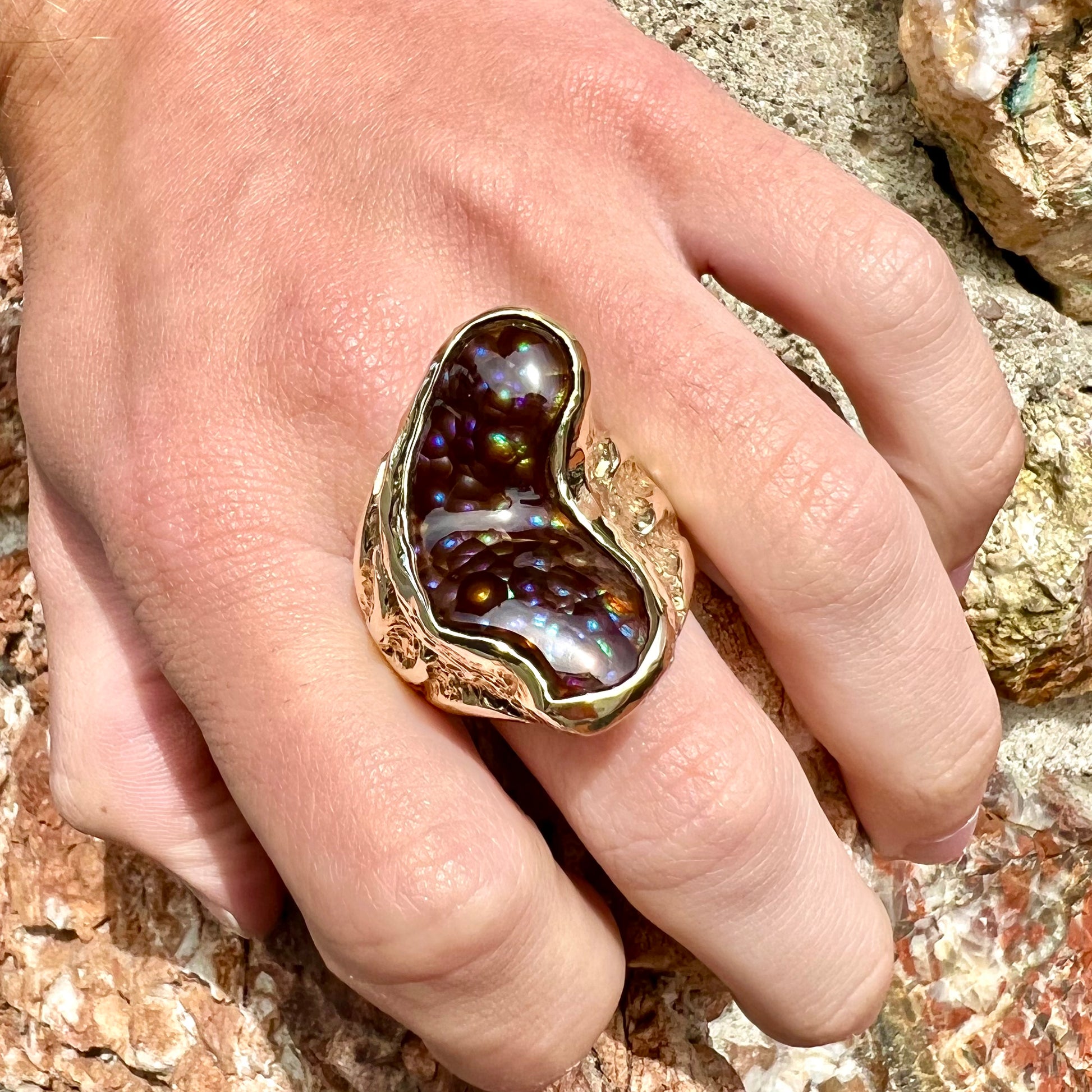 A men's Deer Creek fire agate solitaire ring cast in yellow gold.  The stone is predominantly purple.