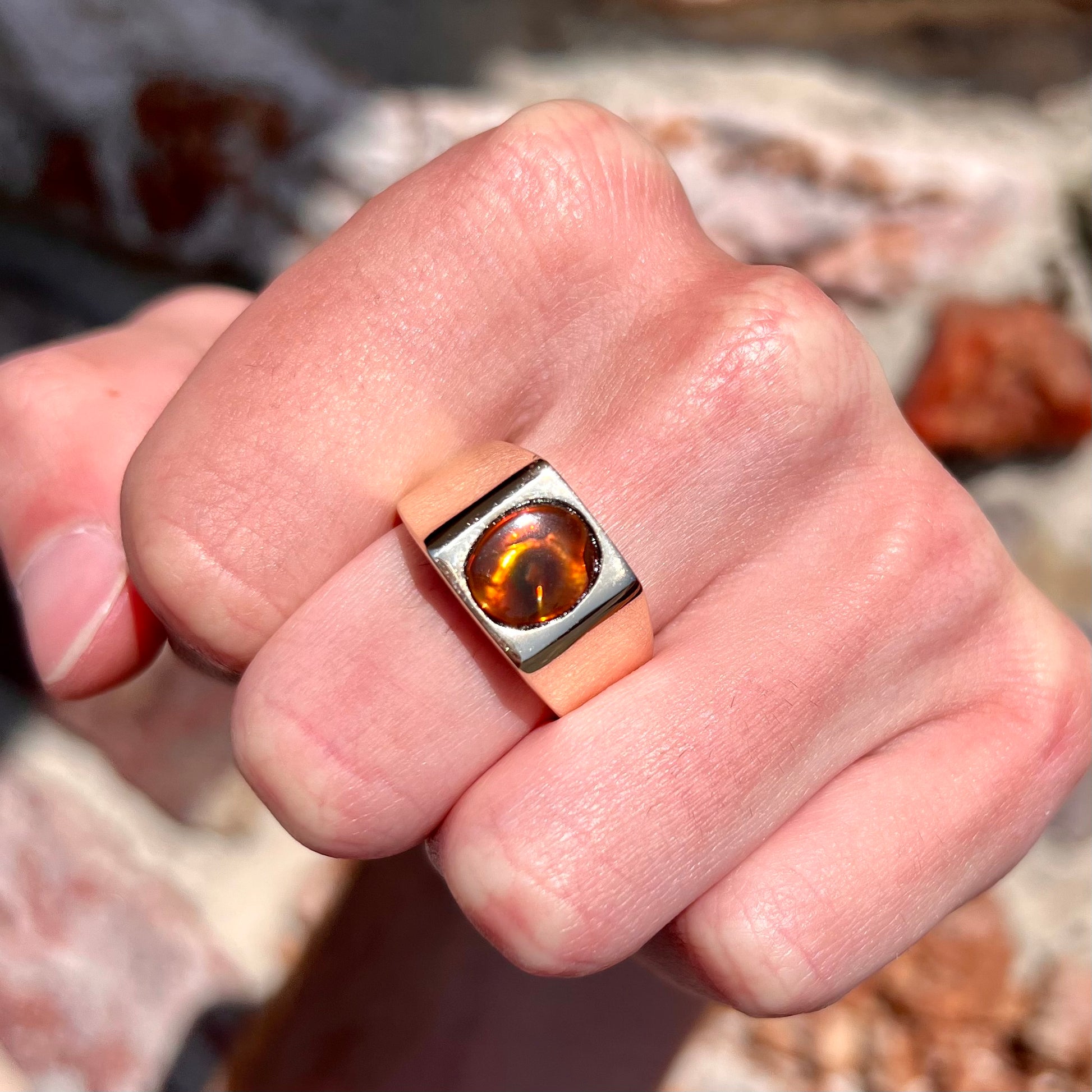 A men's yellow gold flush set fire agate solitaire ring.  The fire agate displays flashes of green, orange, and yellow.