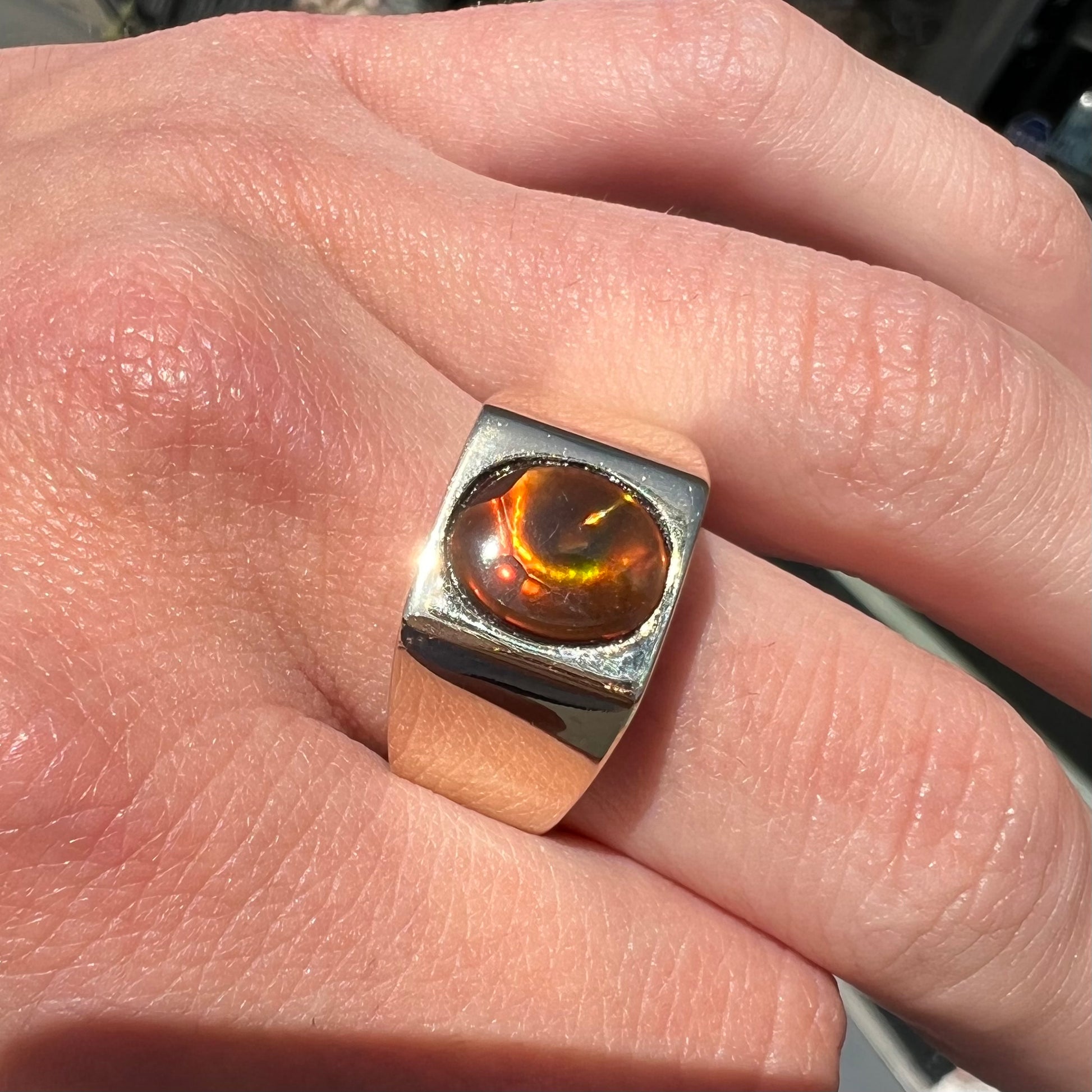 A men's yellow gold flush set fire agate solitaire ring.  The fire agate displays flashes of green, orange, and yellow.