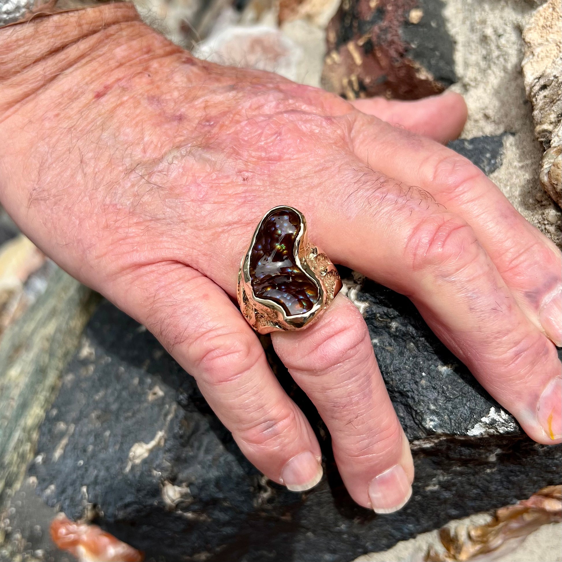 A men's Deer Creek fire agate solitaire ring cast in yellow gold.  The stone is predominantly purple.