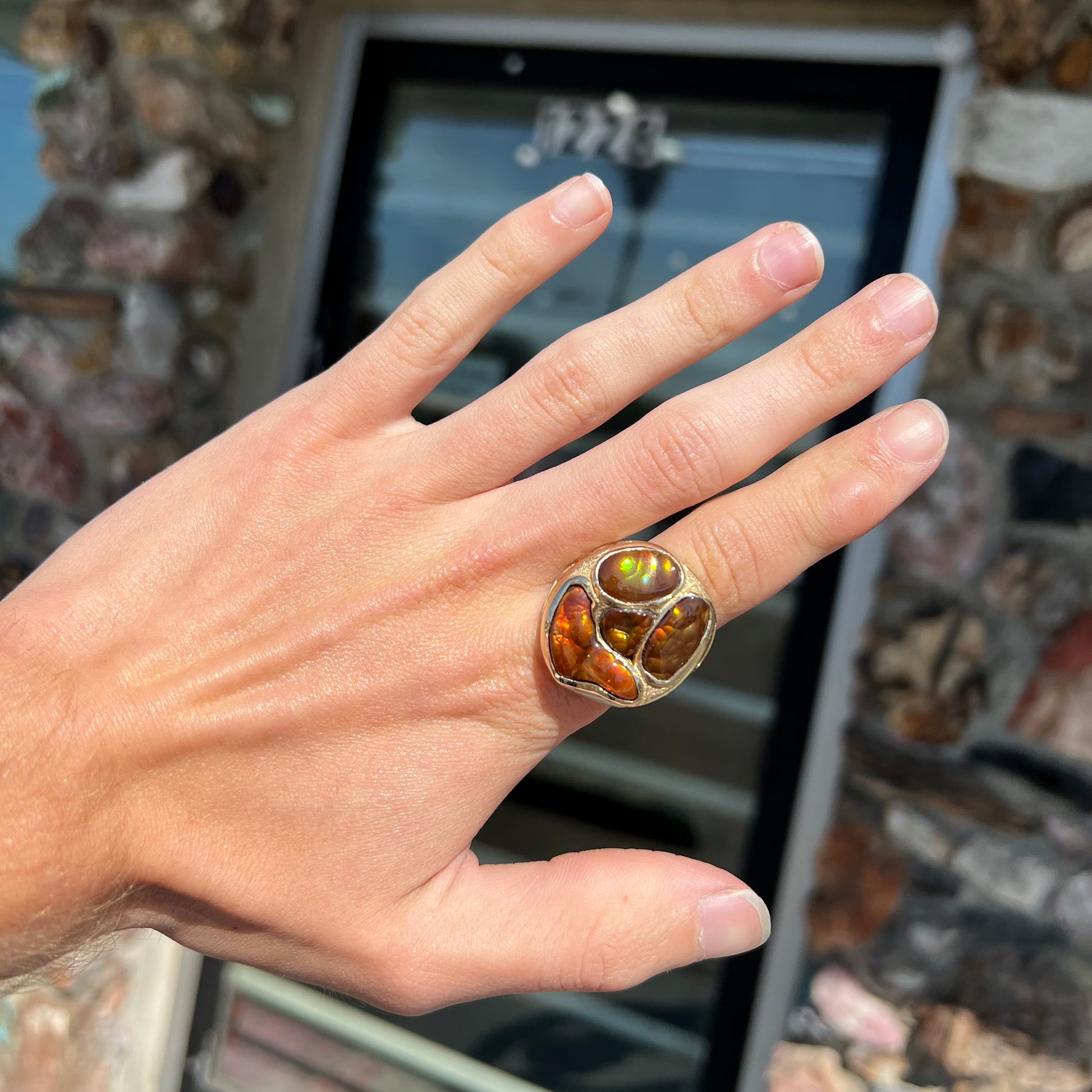 A yellow gold men's thug ring set with four fire agate stones resembling a spooky face.