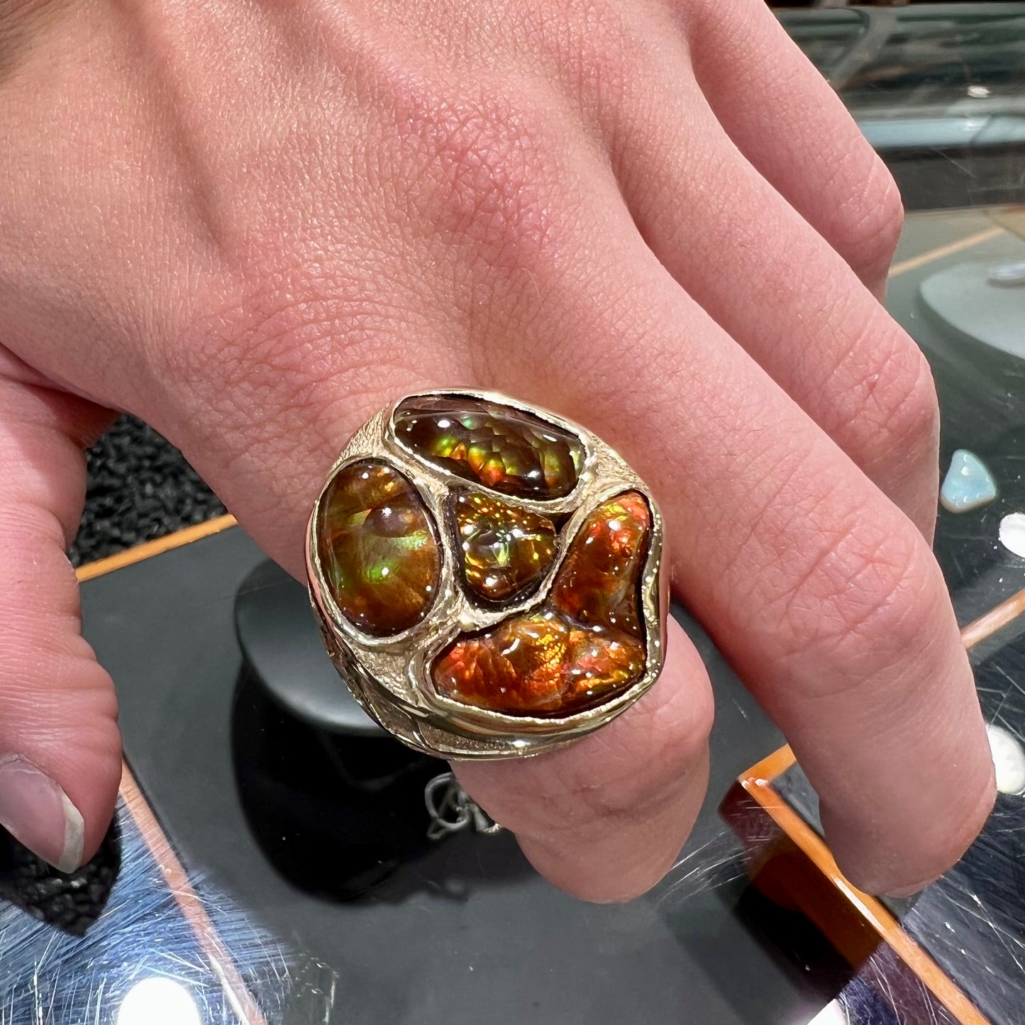 A yellow gold men's thug ring set with four fire agate stones resembling a spooky face.