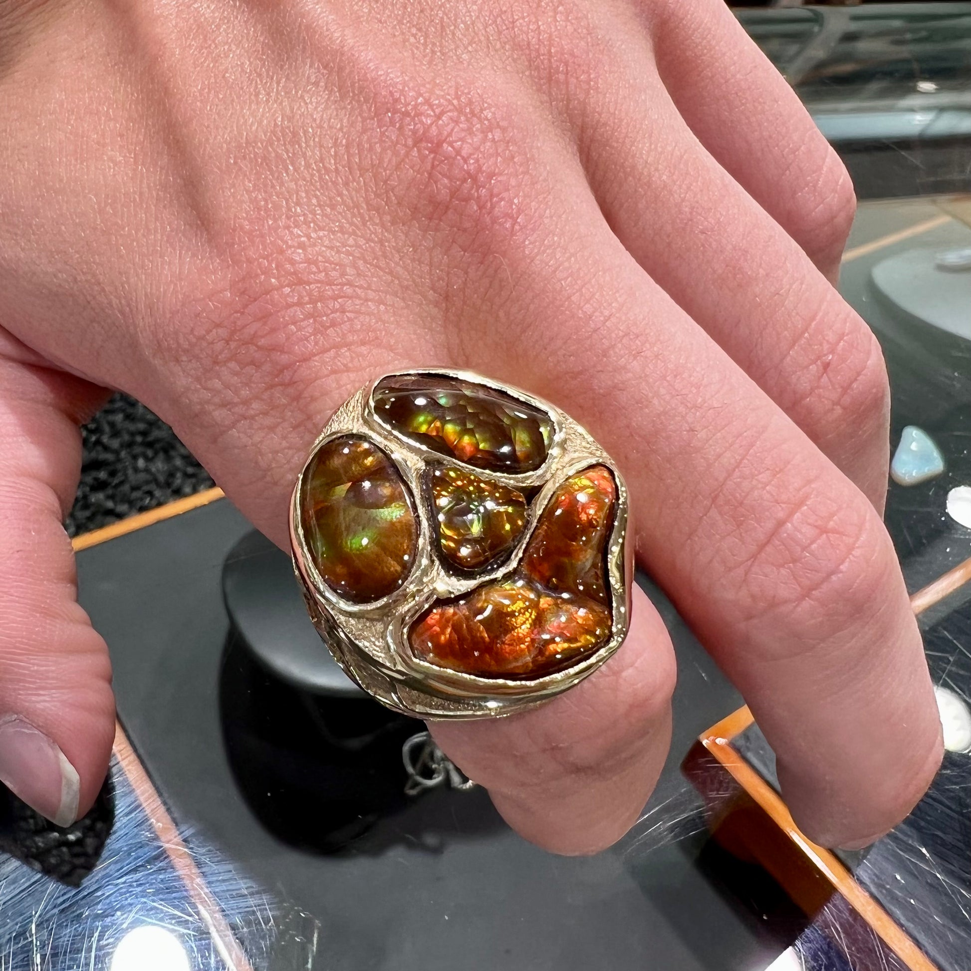 A yellow gold men's thug ring set with four fire agate stones resembling a spooky face.