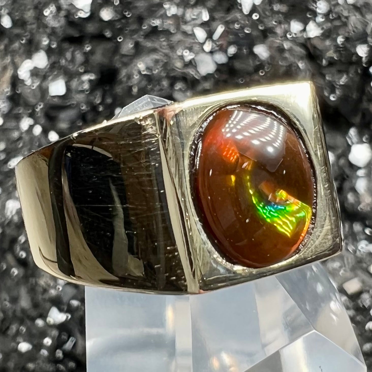 A men's yellow gold flush set fire agate solitaire ring.  The fire agate displays flashes of green, orange, and yellow.