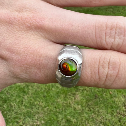 A round cabochon cut red and green fire agate set in a brushed metal white gold men's ring.