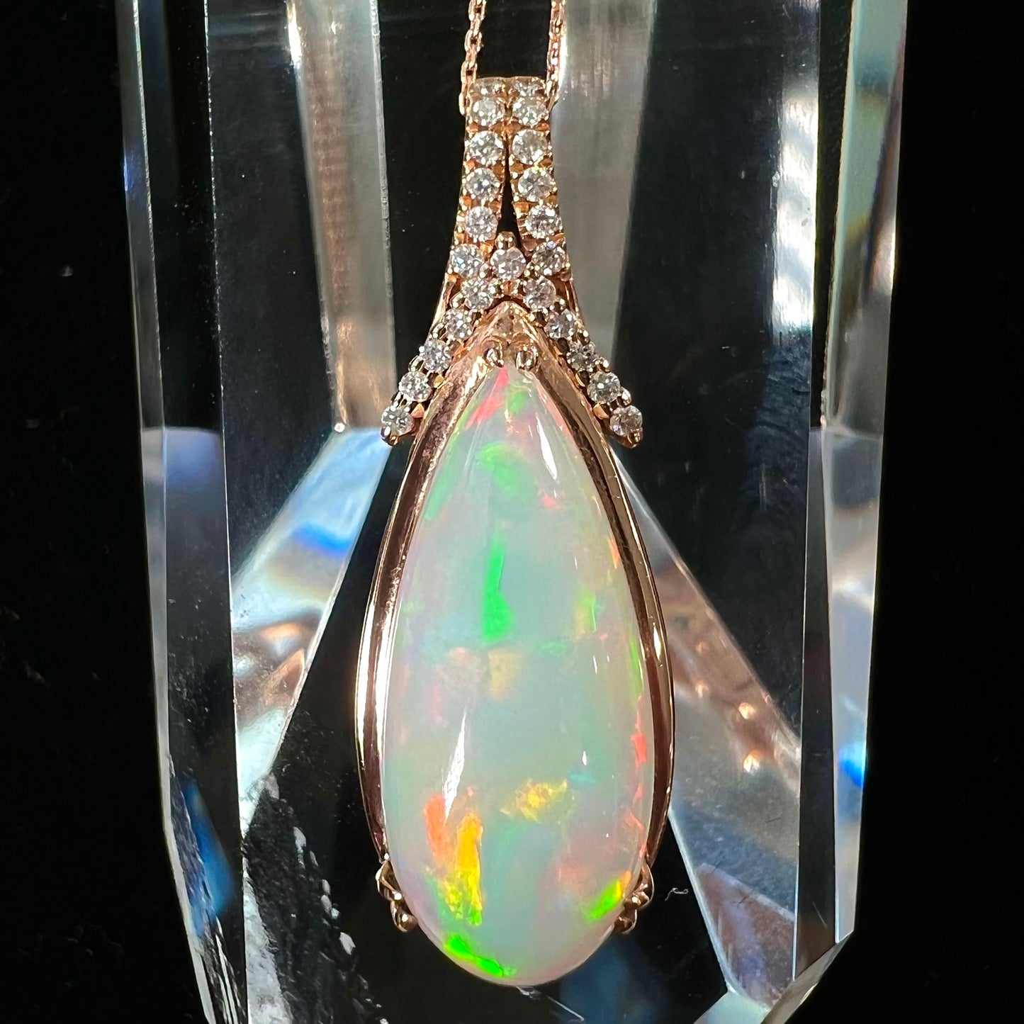 A rose gold, teardrop shaped fire opal and diamond necklace on a cable chain.