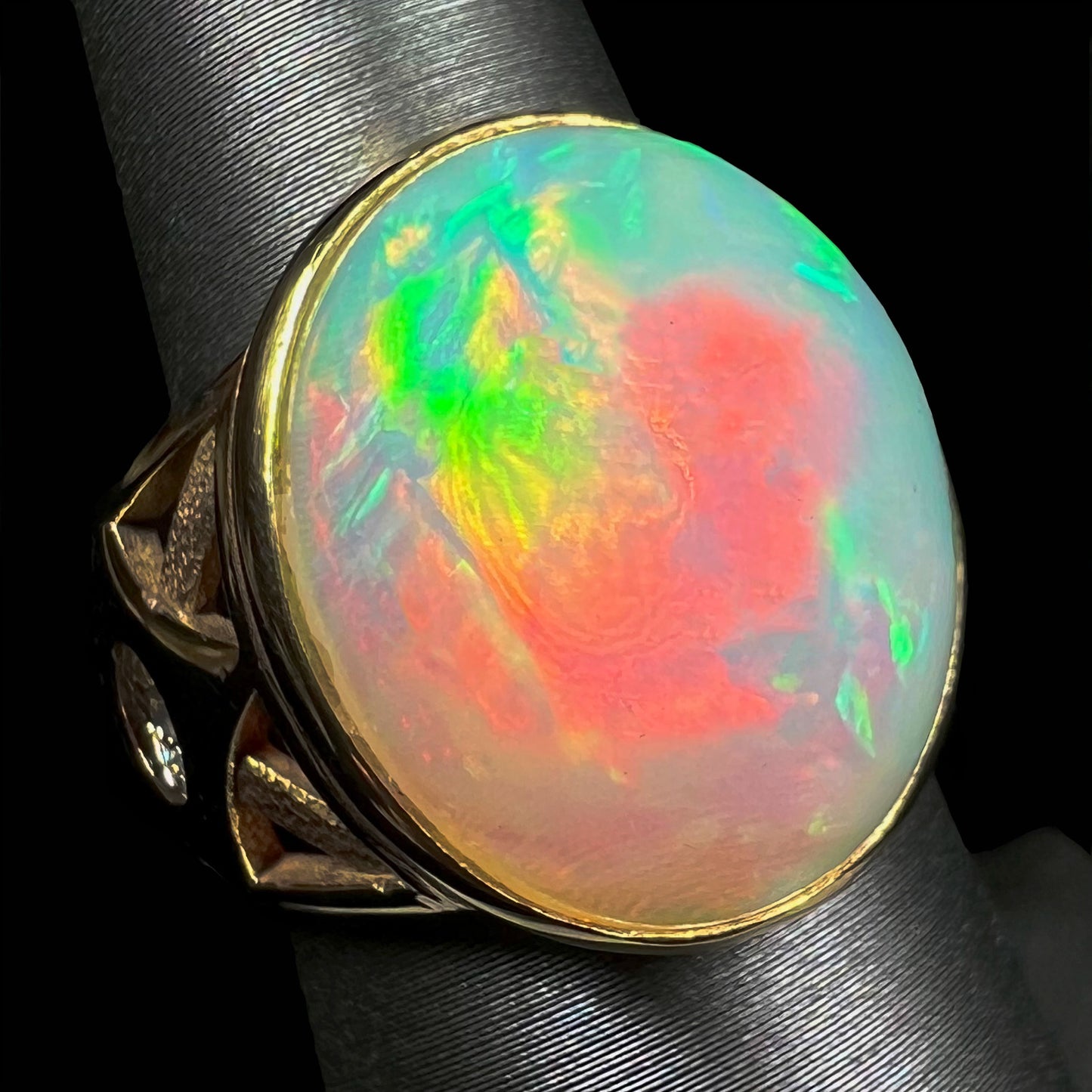 A custom yellow gold men's ring set with two diamonds and a large oval cabochon cut opal from Ethiopia, Africa.