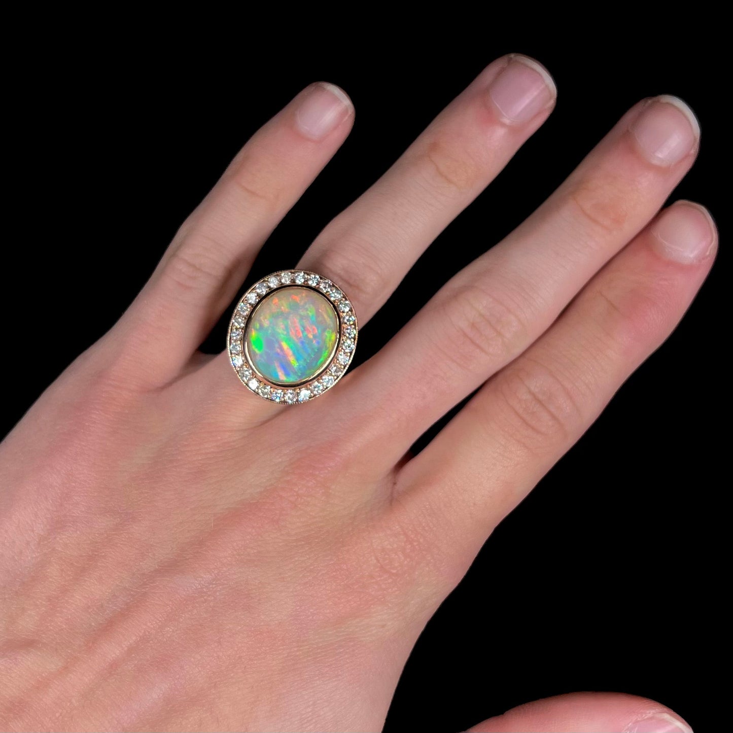 A ladies' natural crystal fire opal ring set in rose gold with a halo of round cut diamonds.