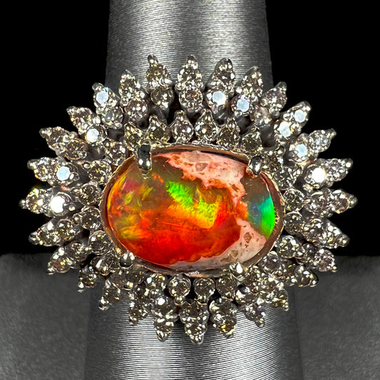 An 18k white gold orange fire opal ring set with a triple halo of diamonds.