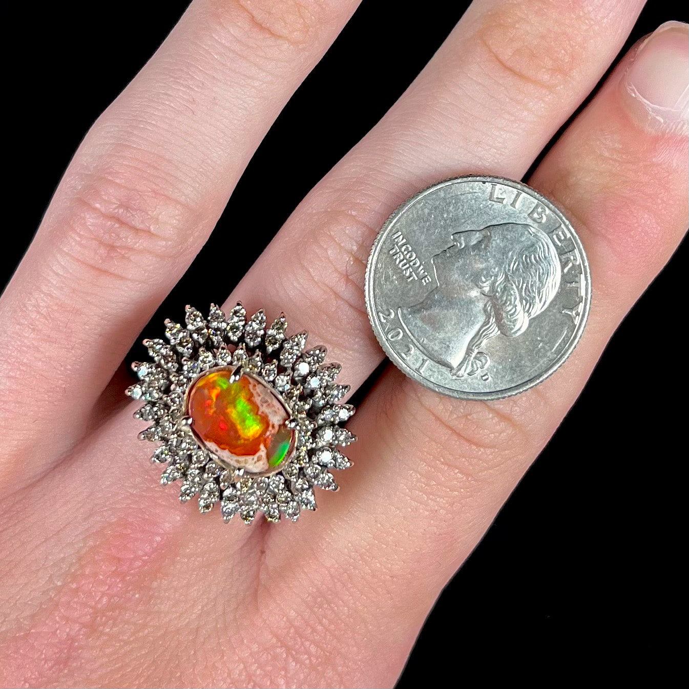 An 18k white gold orange fire opal ring set with a triple halo of diamonds.
