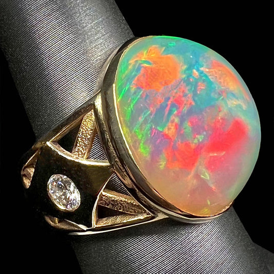 A custom yellow gold men's ring set with two diamonds and a large oval cabochon cut opal from Ethiopia, Africa.