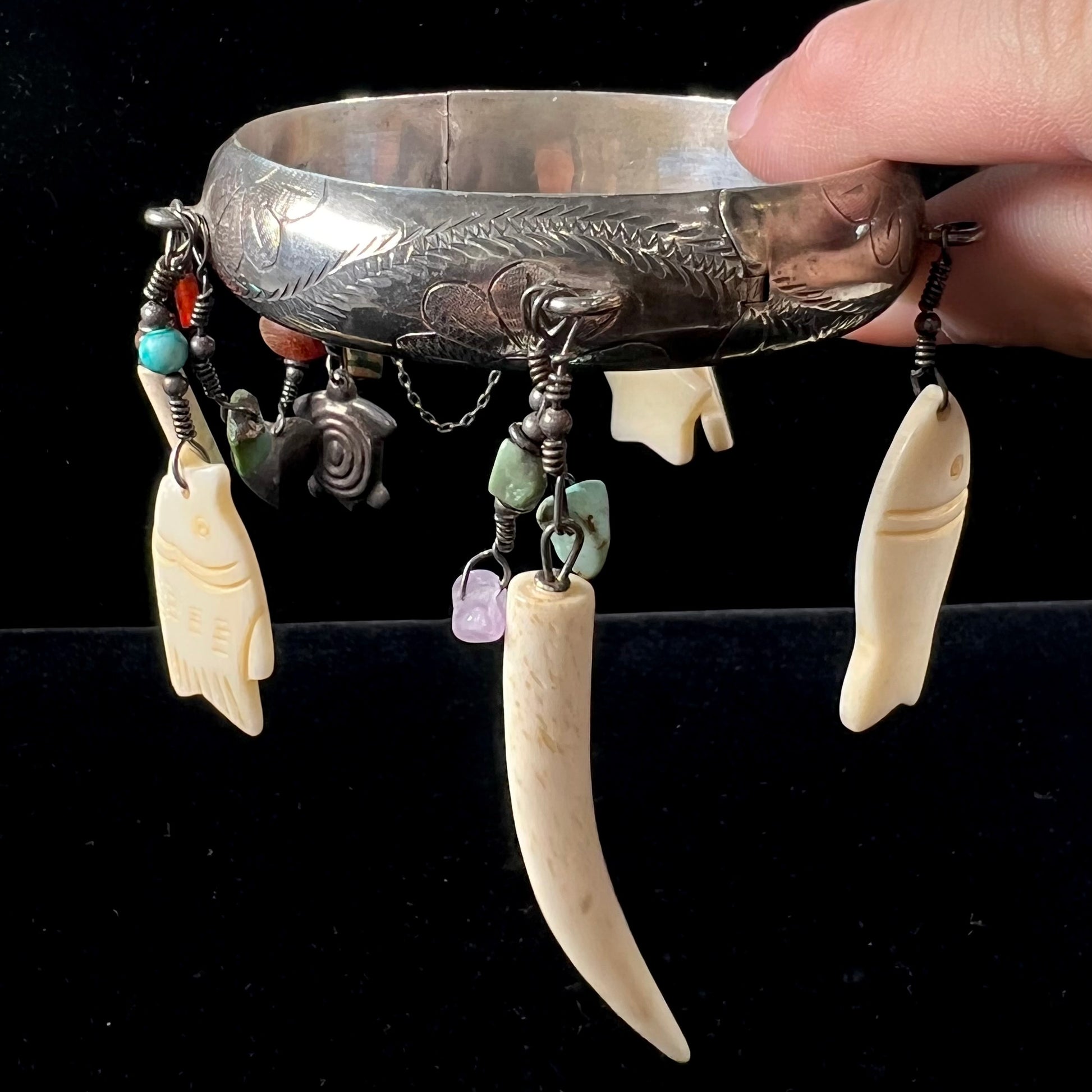 A Native American sterling silver bangle bracelets attached with carved bone, gemstone, and silver charm fetishes.