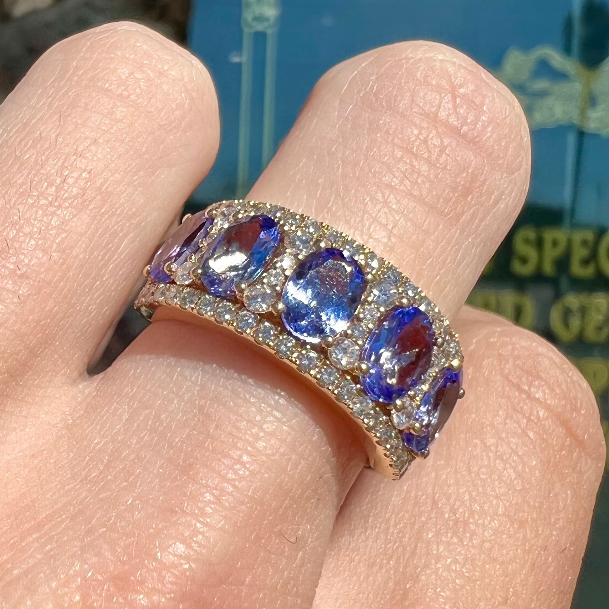 A gold and diamond ladies' band set with five oval cut tanzanite stones.