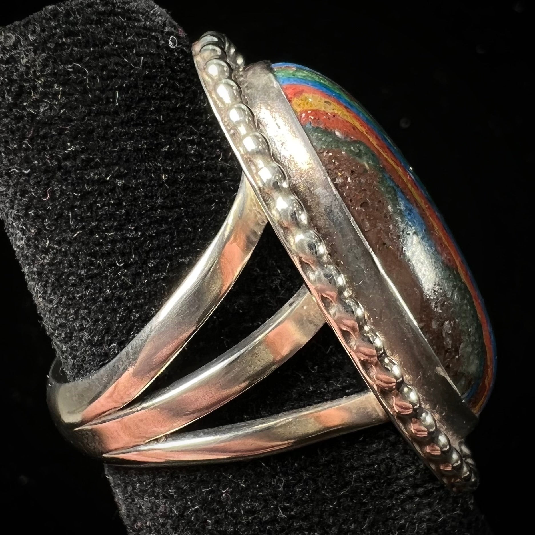 A split shank, rope bezel set silver ring set with an oval cut fordite paint stone.