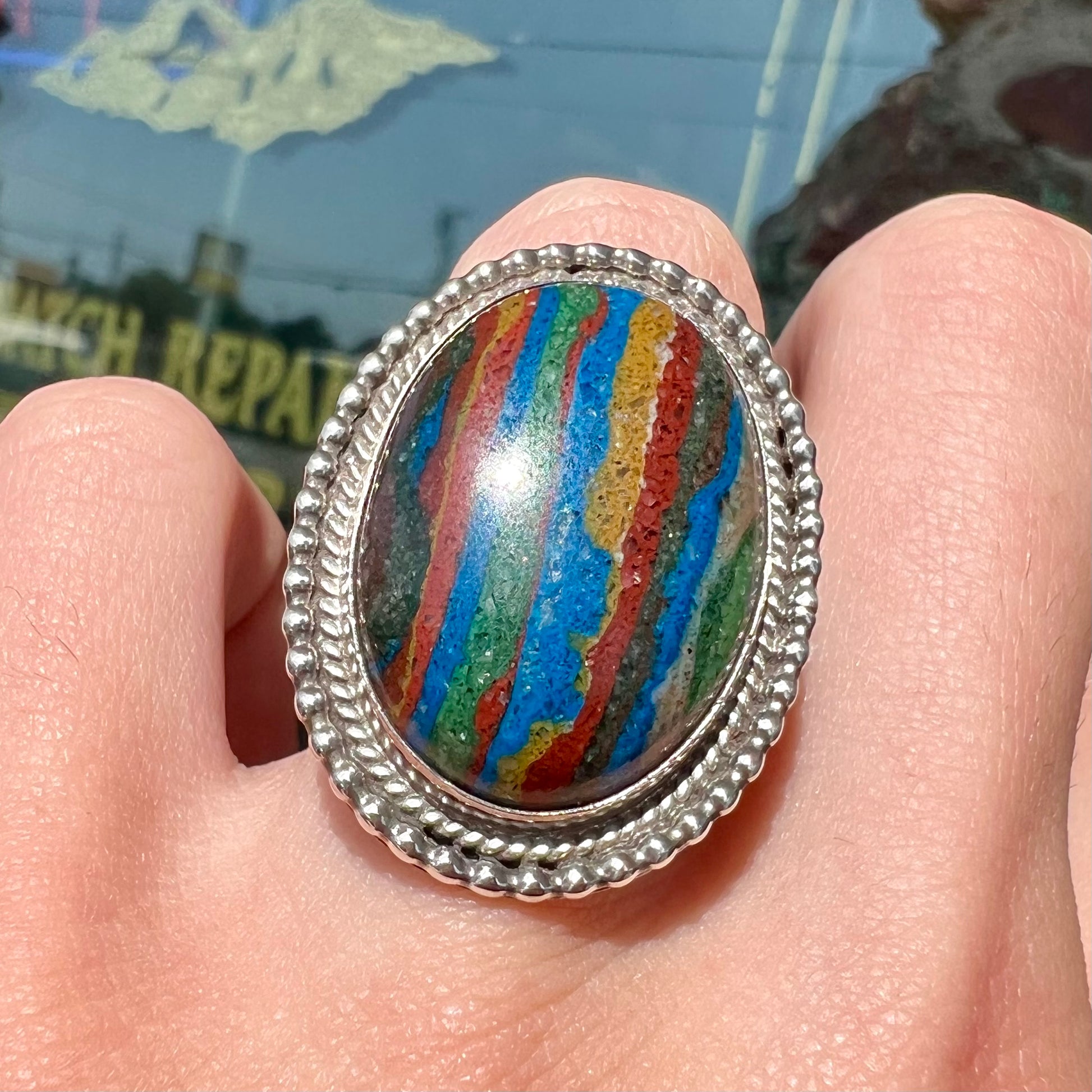 A split shank, rope bezel set silver ring set with an oval cut fordite paint stone.