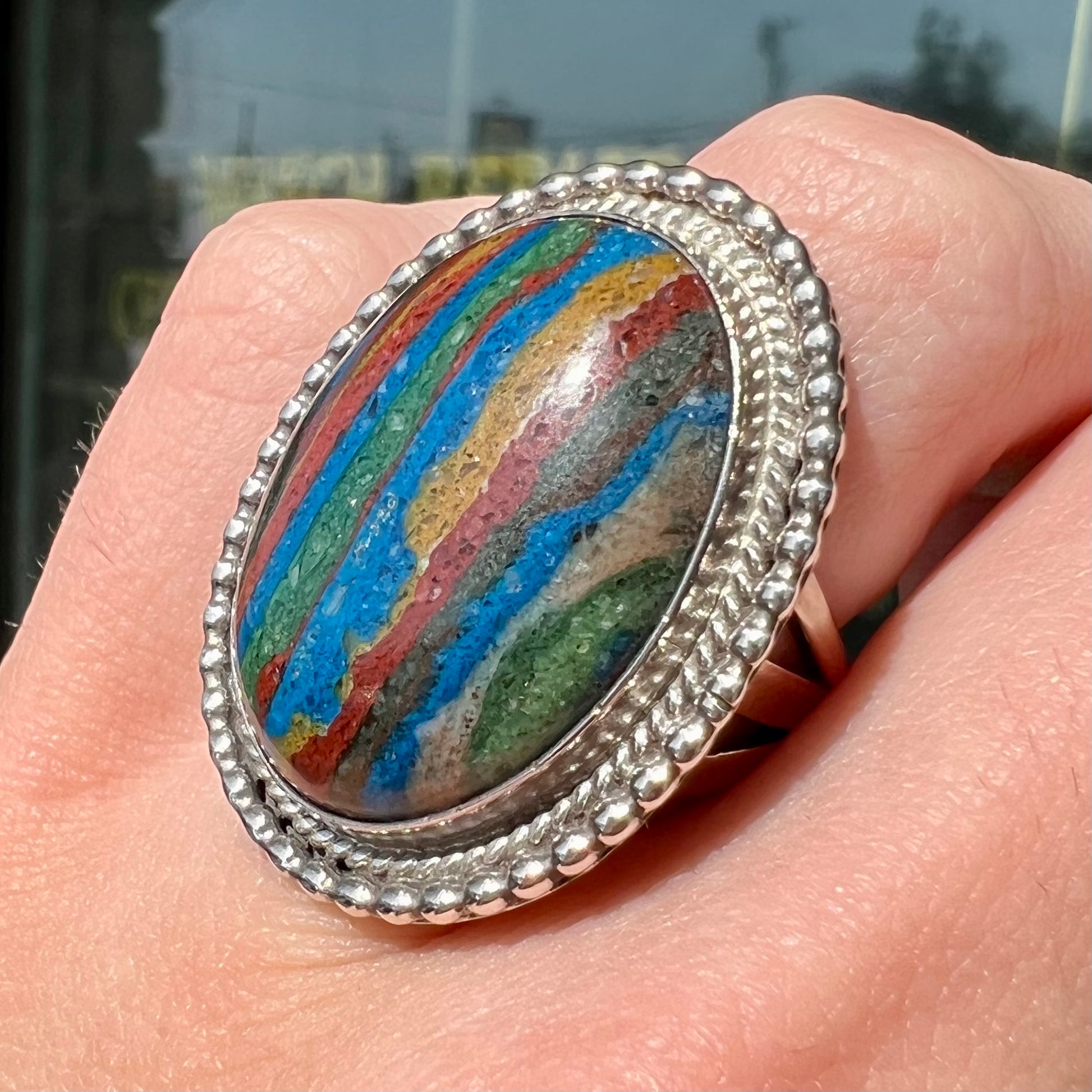 A split shank, rope bezel set silver ring set with an oval cut fordite paint stone.