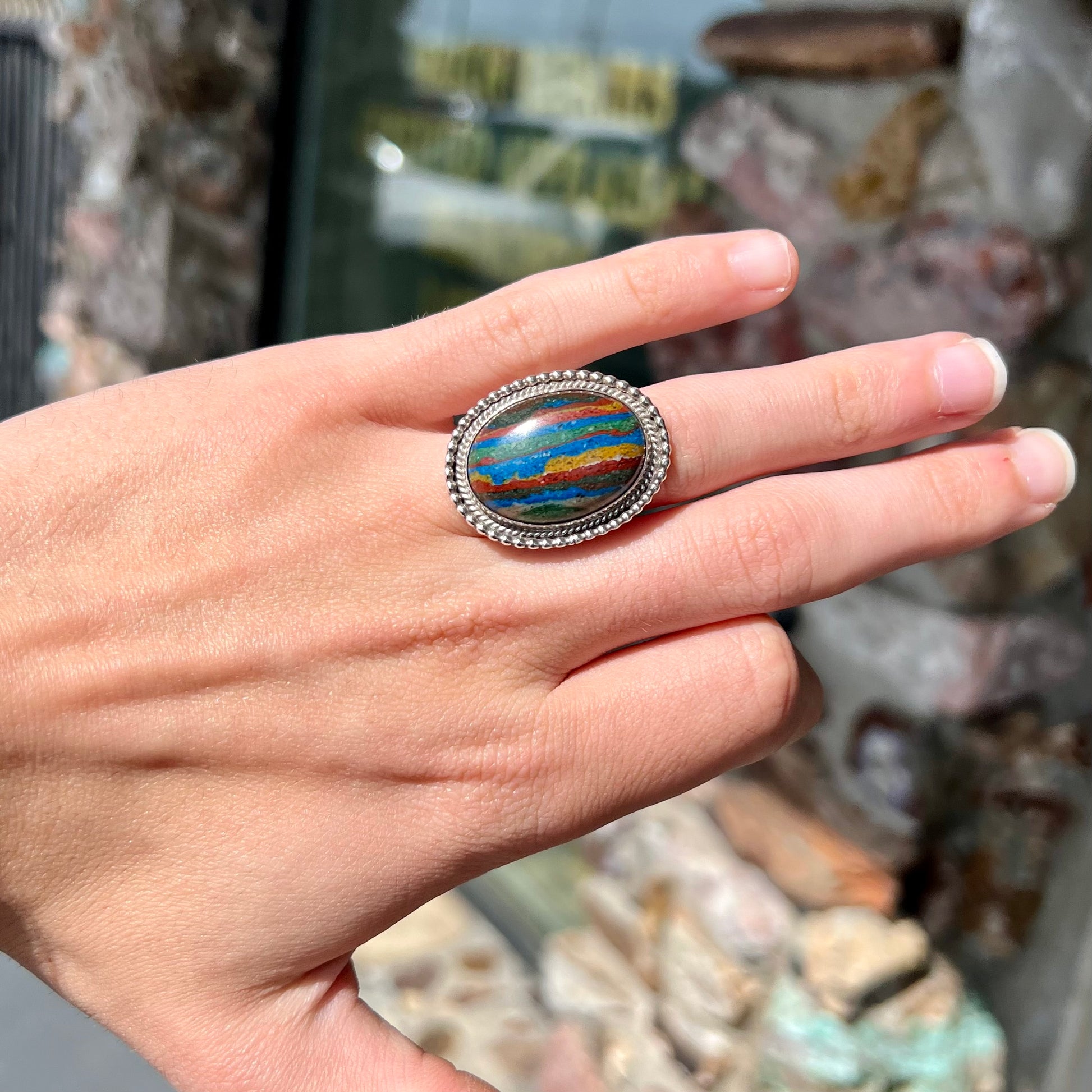 A split shank, rope bezel set silver ring set with an oval cut fordite paint stone.