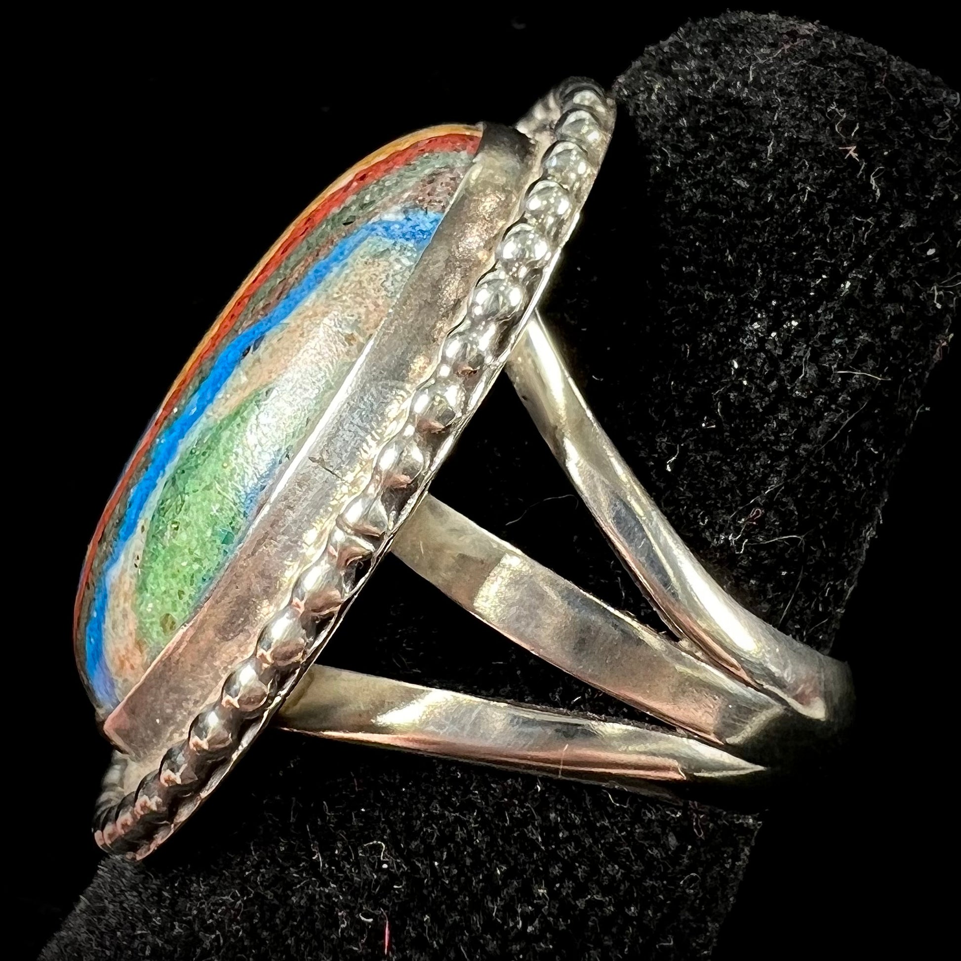 A split shank, rope bezel set silver ring set with an oval cut fordite paint stone.