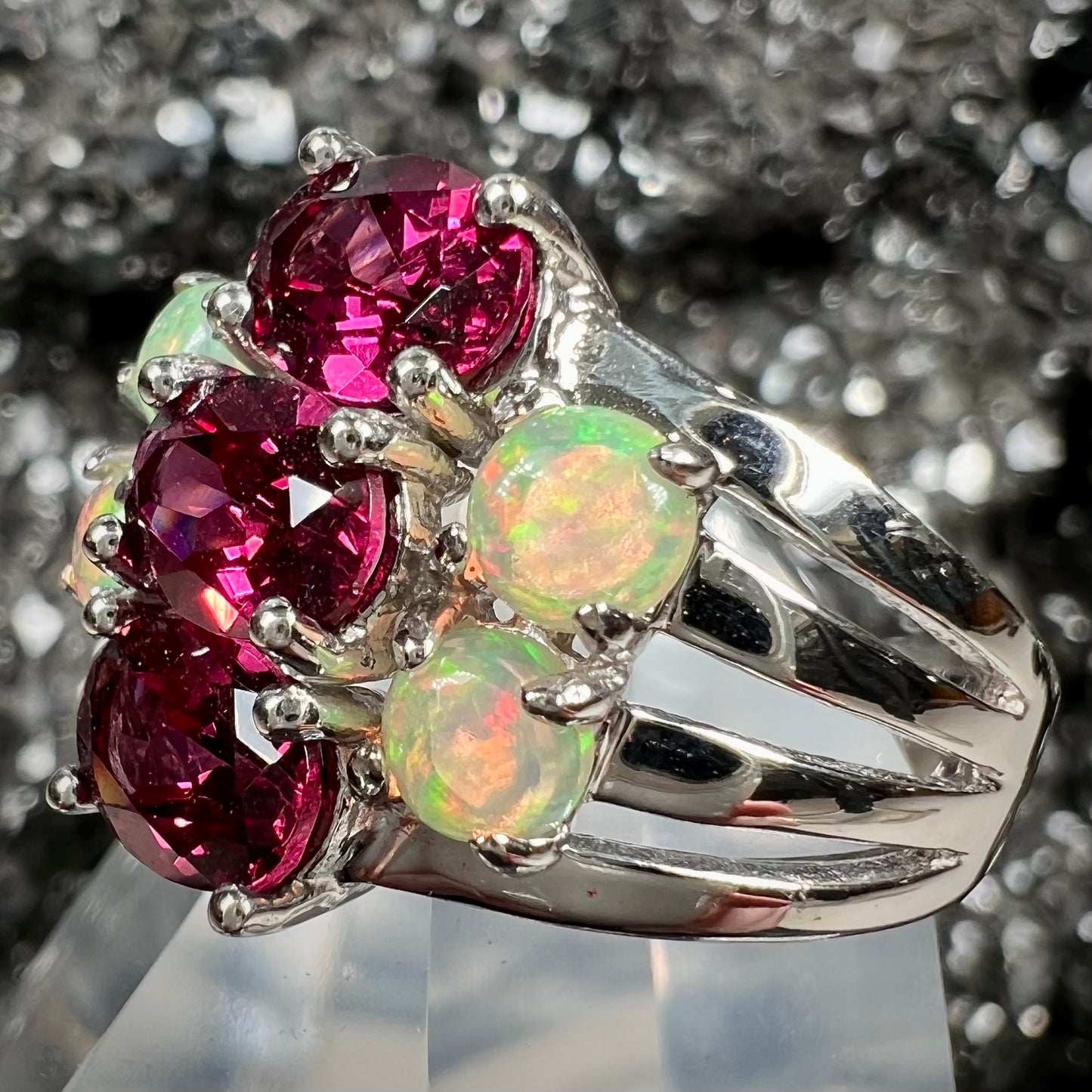 A sterling silver ring set with three oval cut rhodolite garnets and four round cabochon cut Ethiopian opals.
