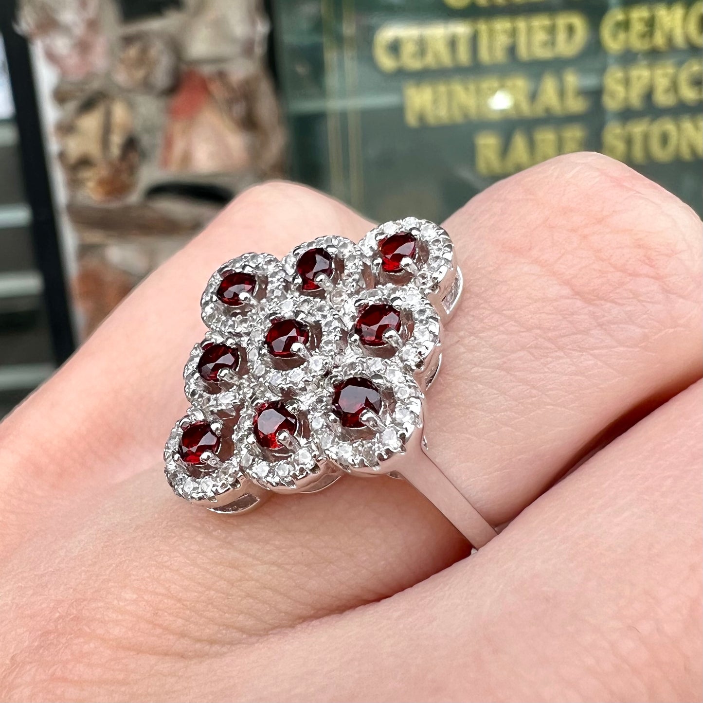 A sterling silver cluster ring set with round almandine garnet main stones and white zircon accents.