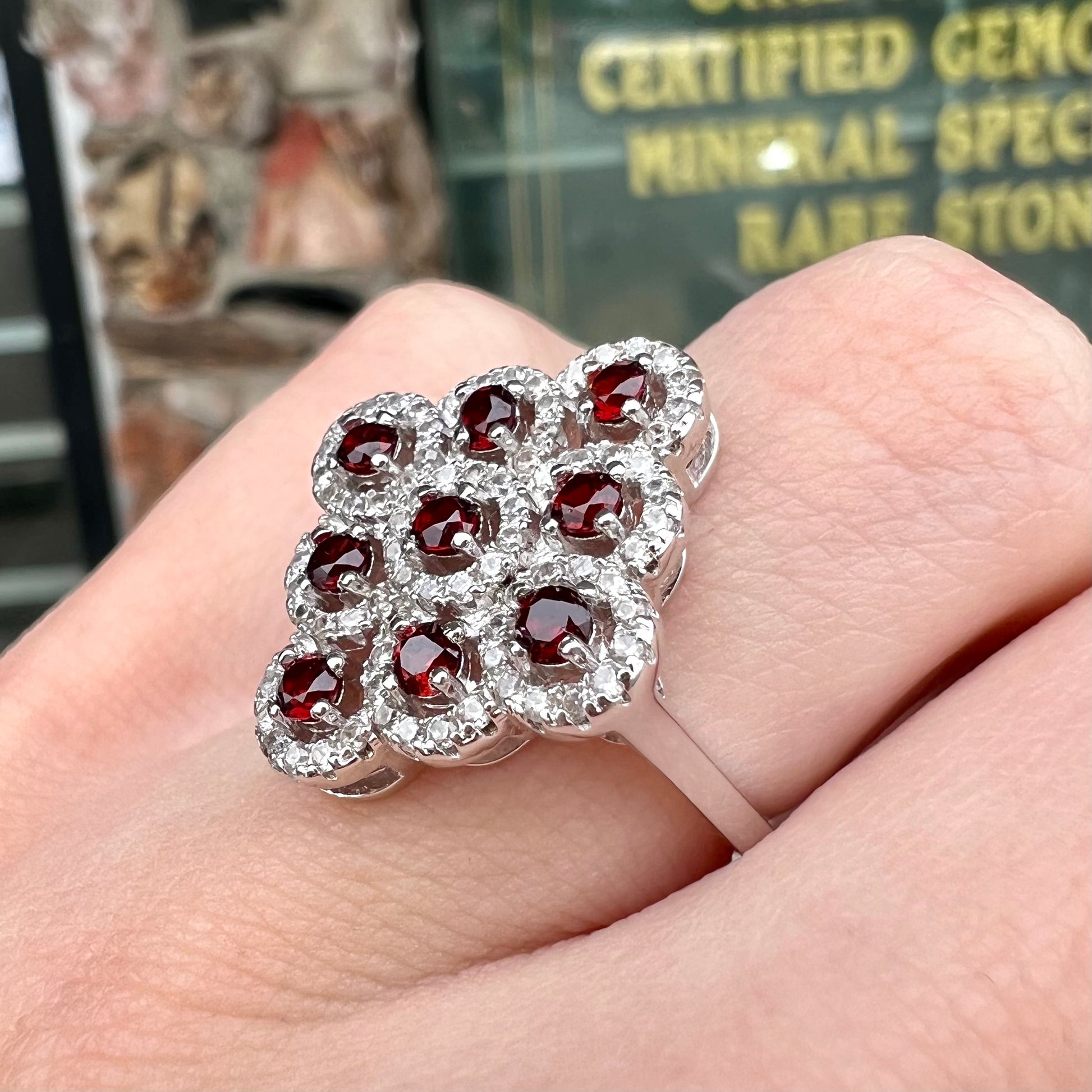 A sterling silver cluster ring set with round almandine garnet main stones and white zircon accents.