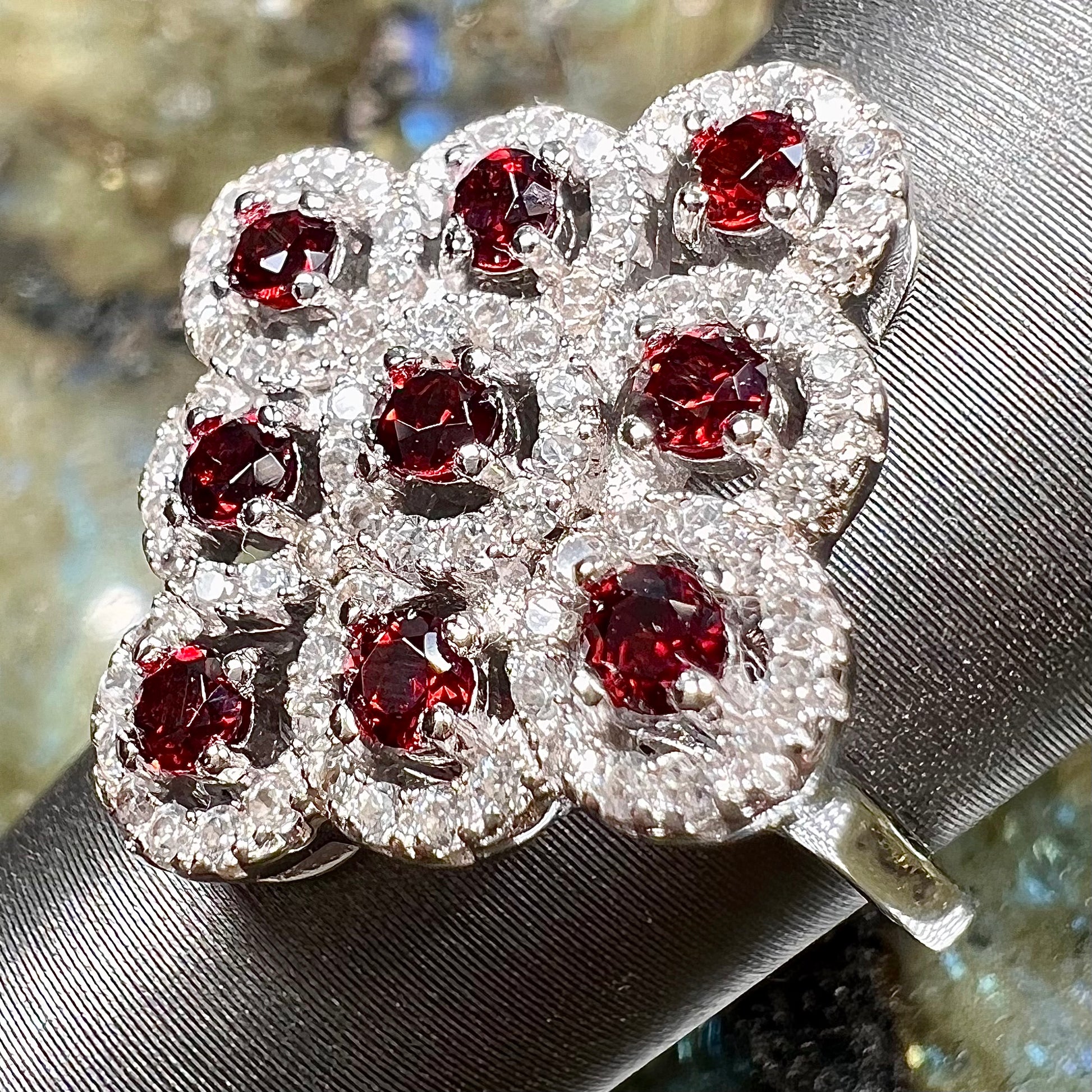 A sterling silver cluster ring set with round almandine garnet main stones and white zircon accents.