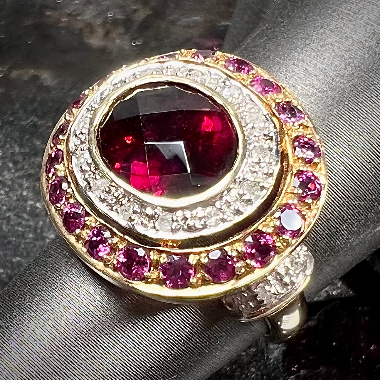 A yellow gold garnet and diamond halo ring set with a checkerboard cut rhodolite garnet center stone.