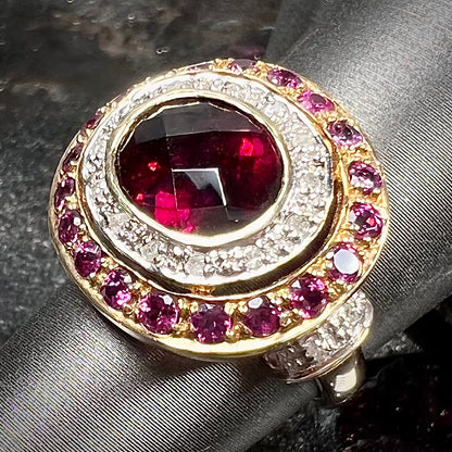 A yellow gold garnet and diamond halo ring set with a checkerboard cut rhodolite garnet center stone.