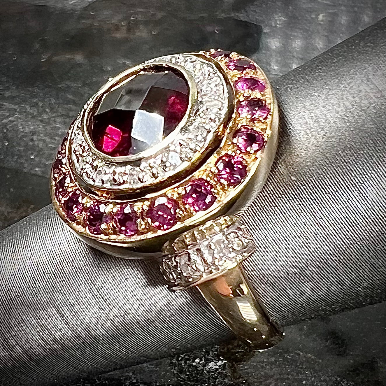 A yellow gold garnet and diamond halo ring set with a checkerboard cut rhodolite garnet center stone.