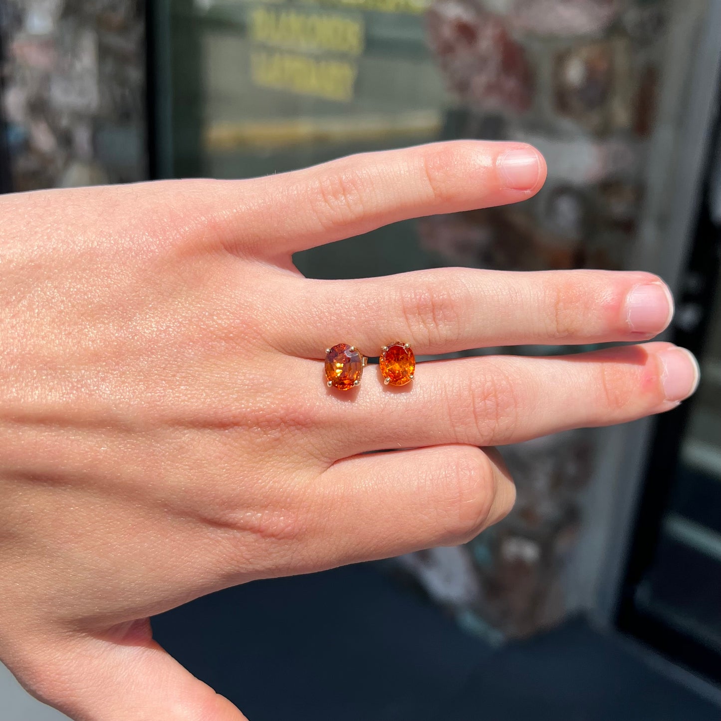 A pair of yellow gold orange hessonite garnet stud earrings.  The garnets are faceted oval cut.