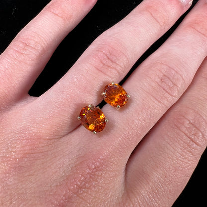 A pair of yellow gold orange hessonite garnet stud earrings.  The garnets are faceted oval cut.