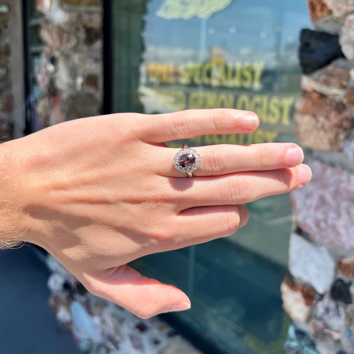 A white gold diamond halo ring set with a purplish faceted oval cut color change garnet.