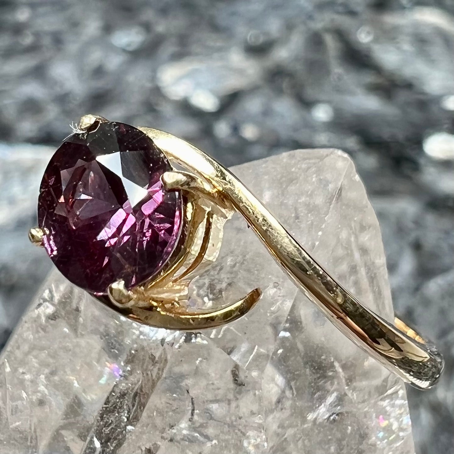 A yellow gold solitaire engagement ring set with a faceted oval cut color change garnet stone.