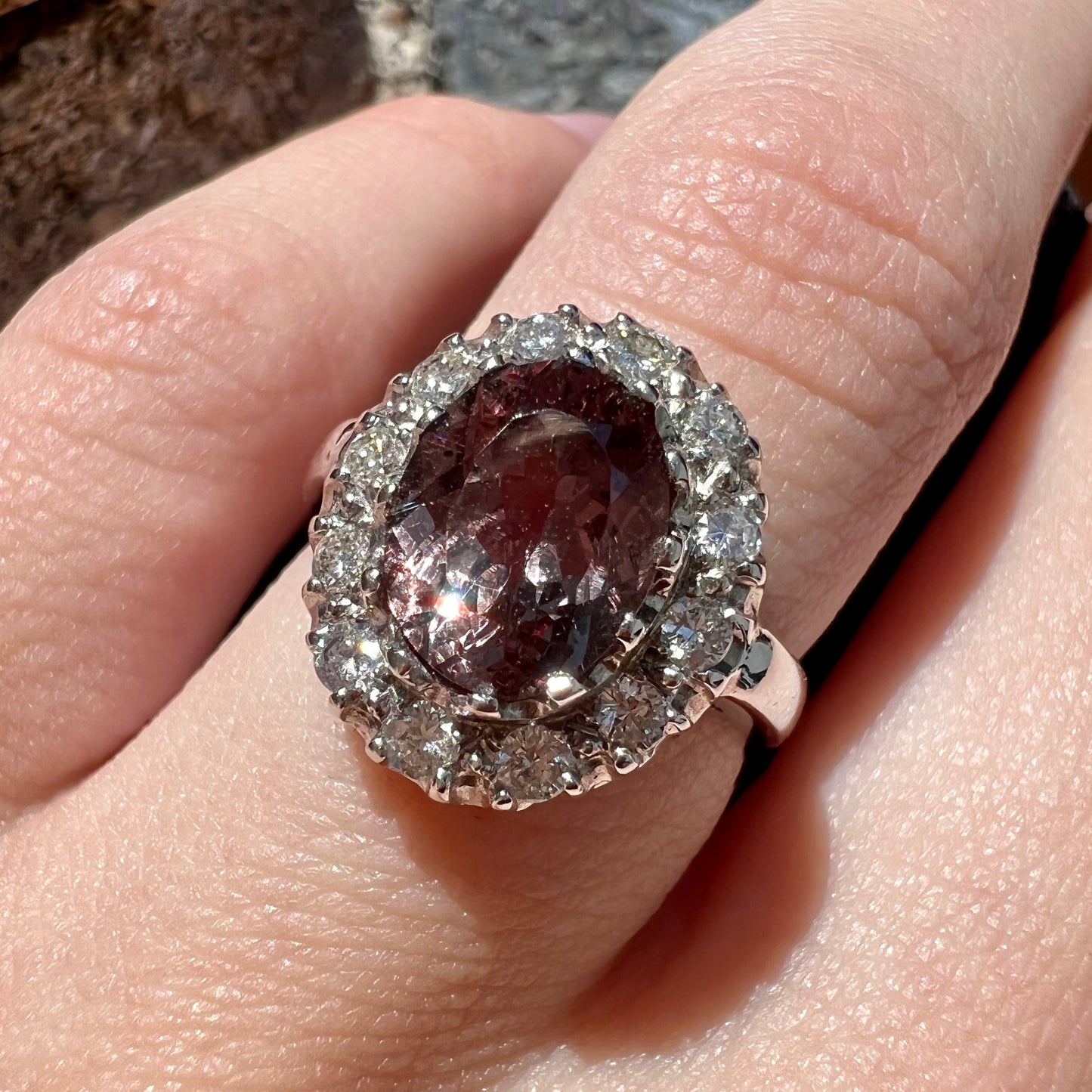 A white gold diamond halo ring set with a purplish faceted oval cut color change garnet.