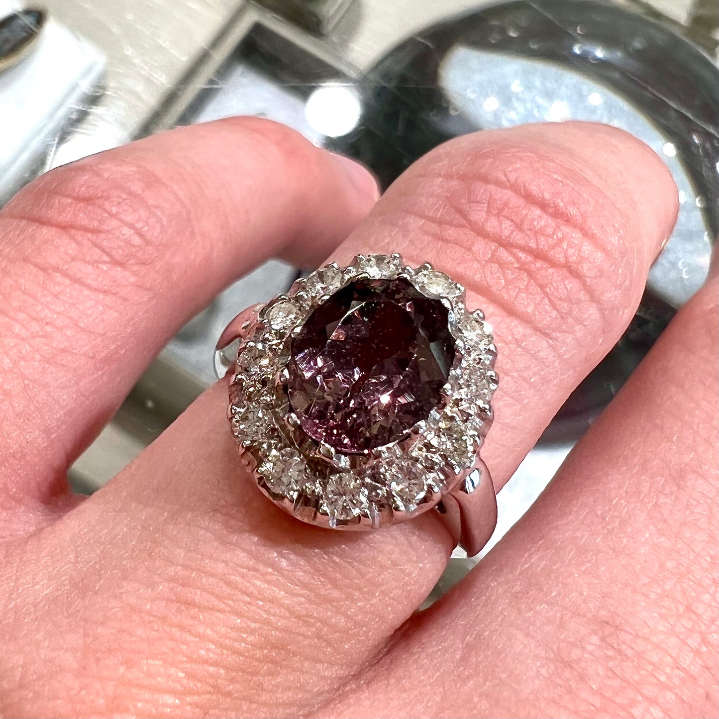 A white gold diamond halo ring set with a purplish faceted oval cut color change garnet.