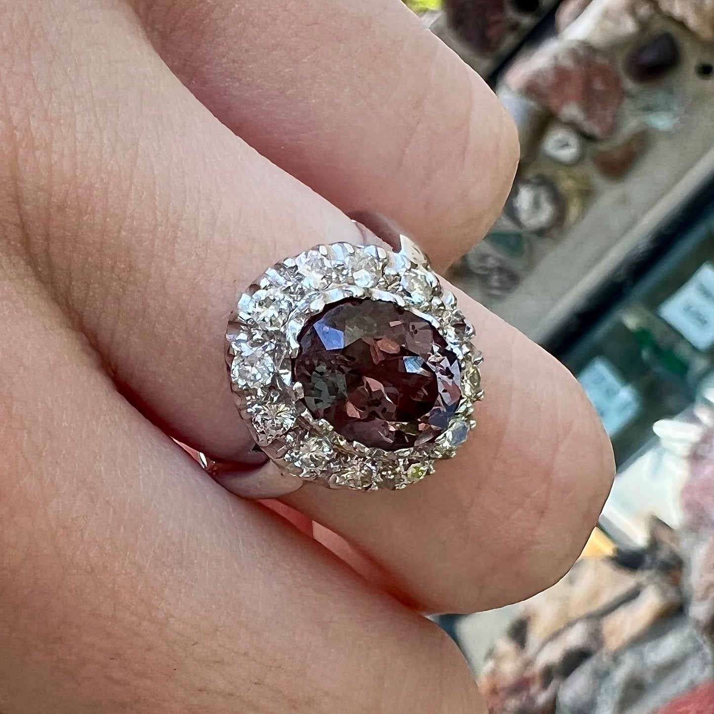 A white gold diamond halo ring set with a purplish faceted oval cut color change garnet.