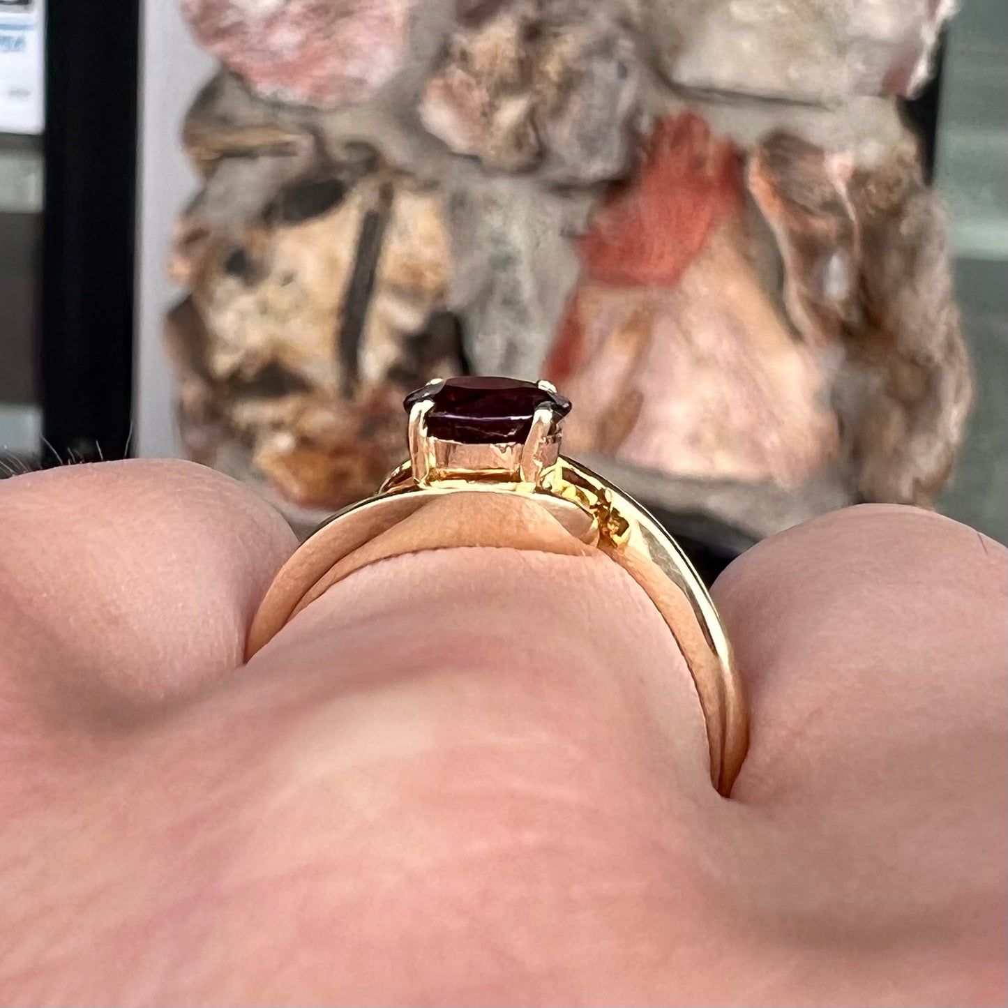 A yellow gold solitaire engagement ring set with a faceted oval cut color change garnet stone.