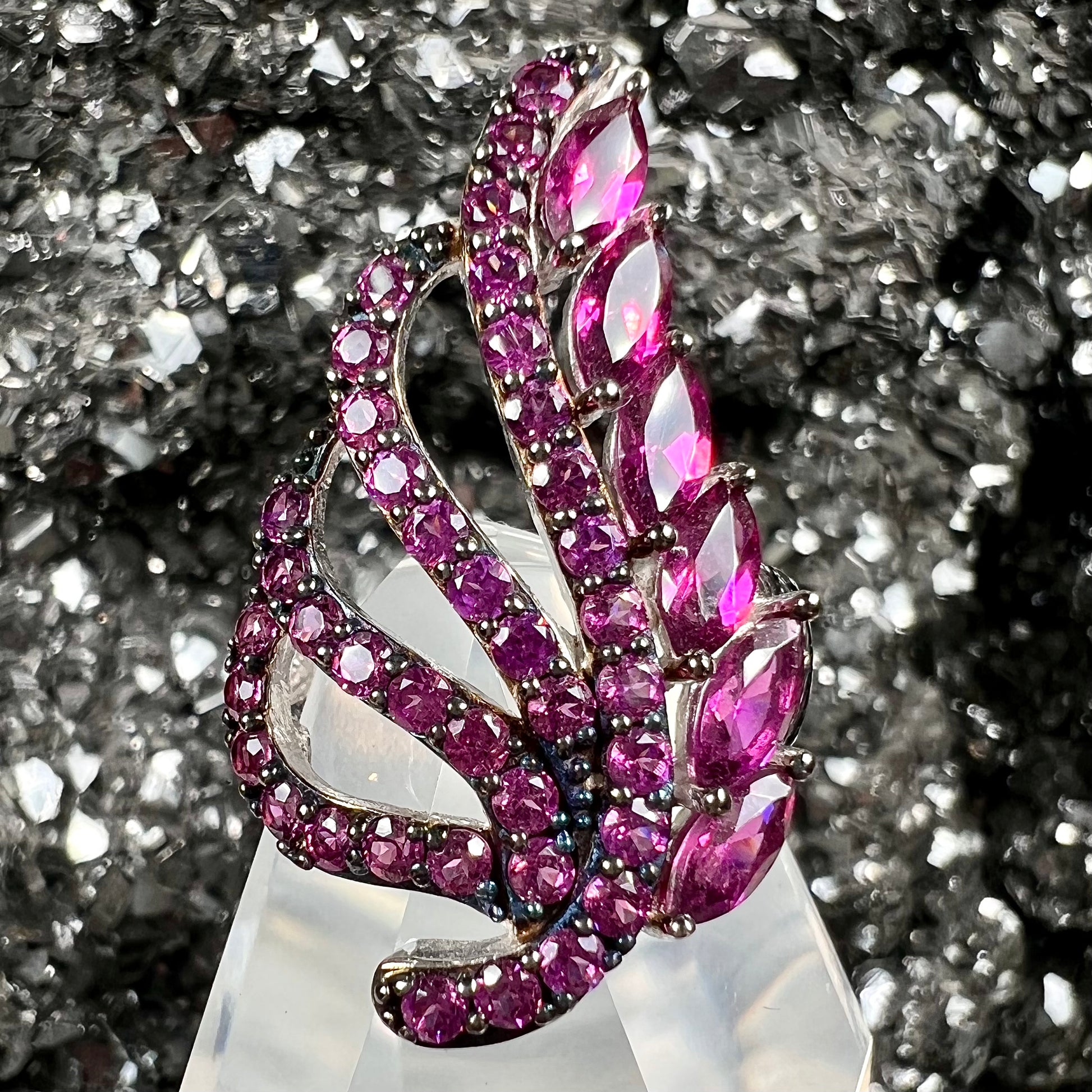 A sterling silver, feather shaped ring set with round and marquise cut rhodolite garnet stones.
