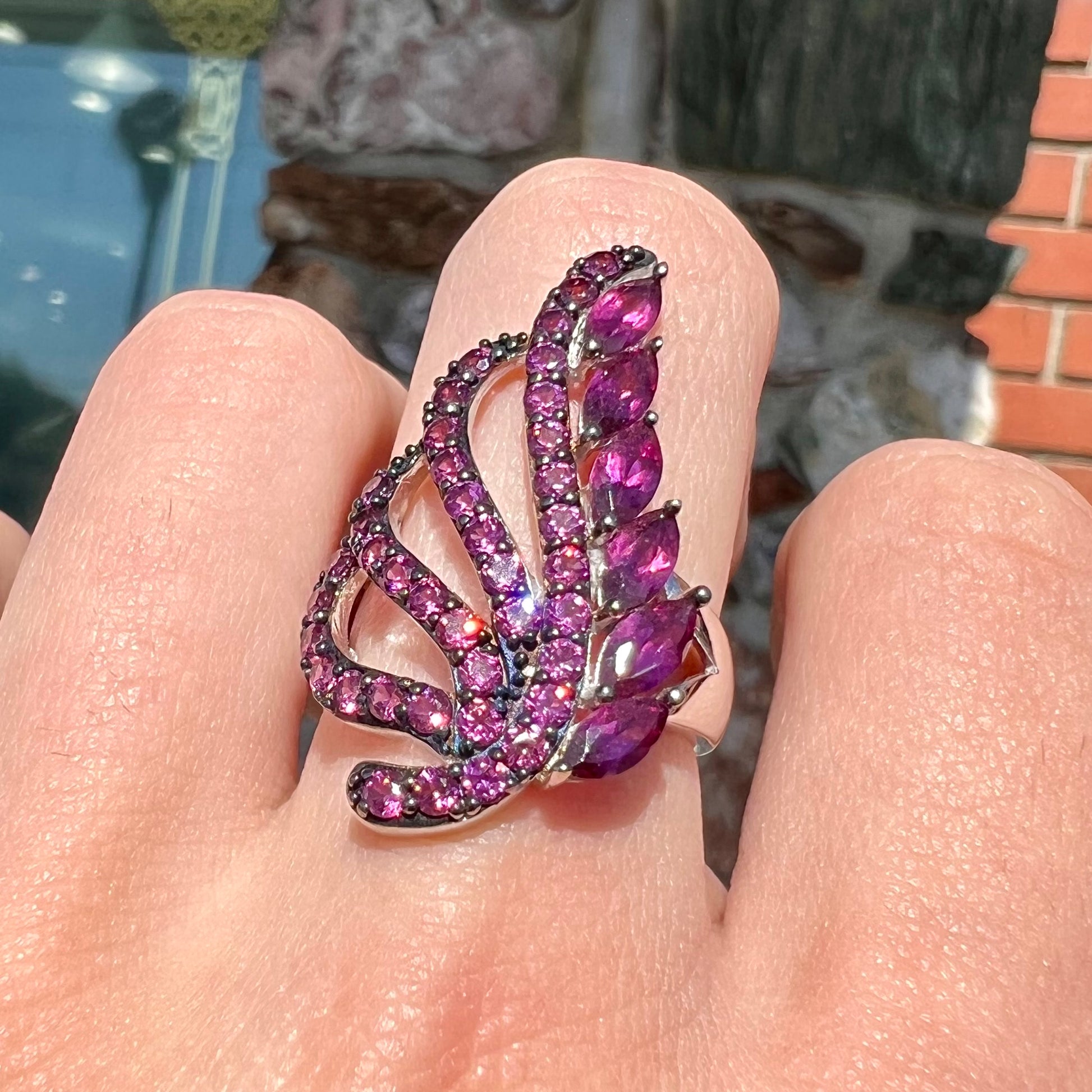 A sterling silver, feather shaped ring set with round and marquise cut rhodolite garnet stones.